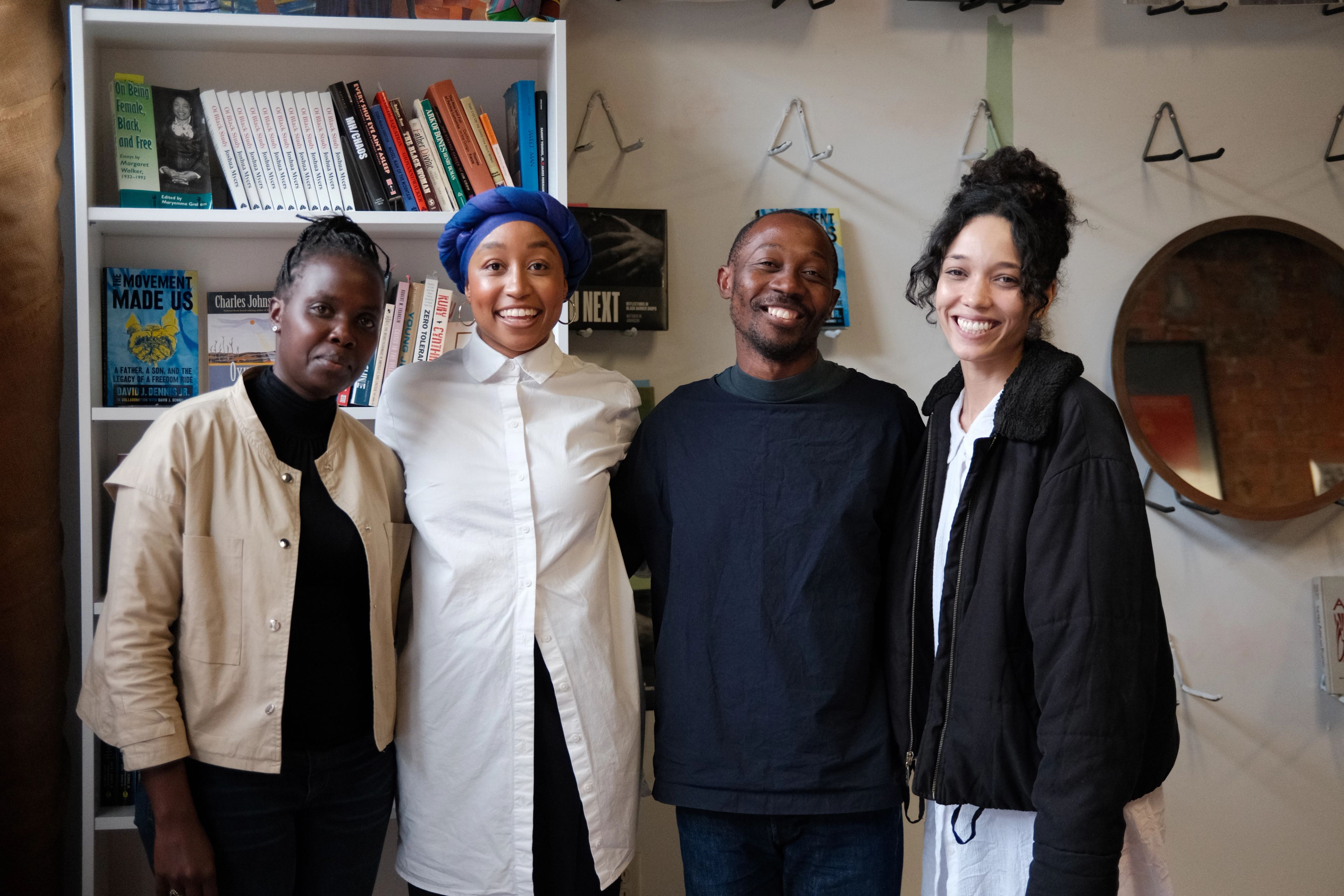 Four people smiling and standing in front of a bookshelf.