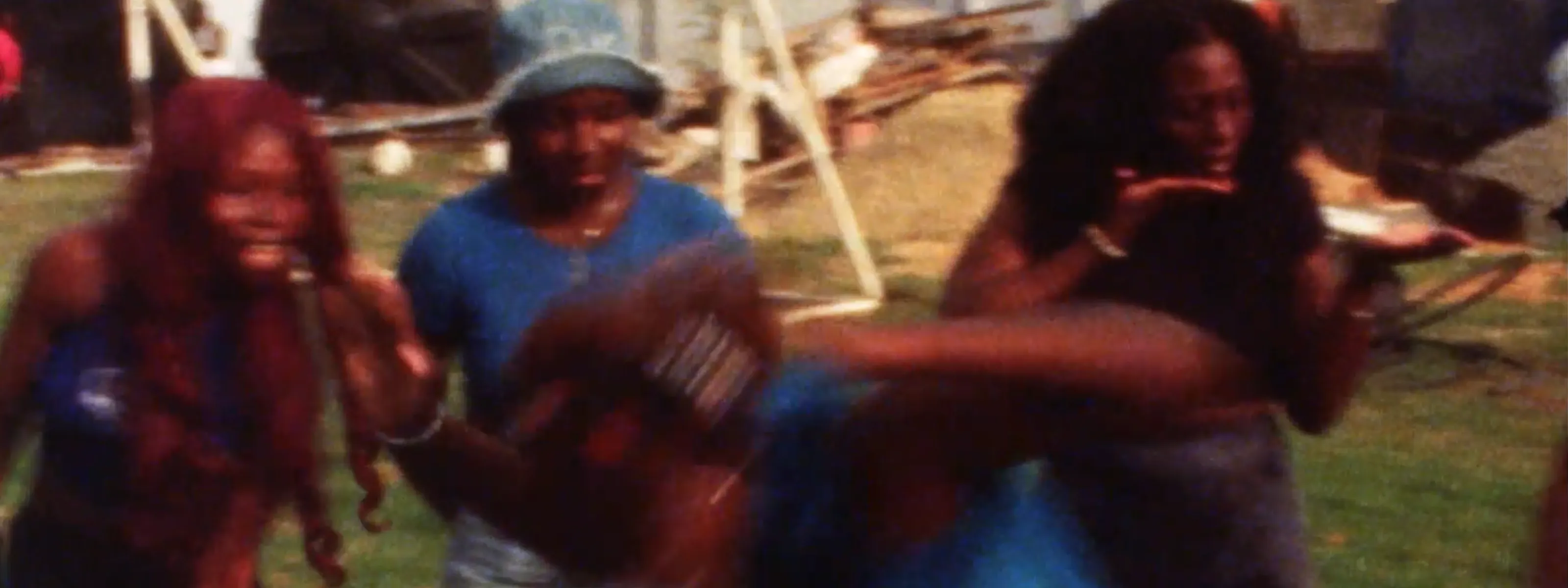 Four blurry Black women are in motion outdoors.