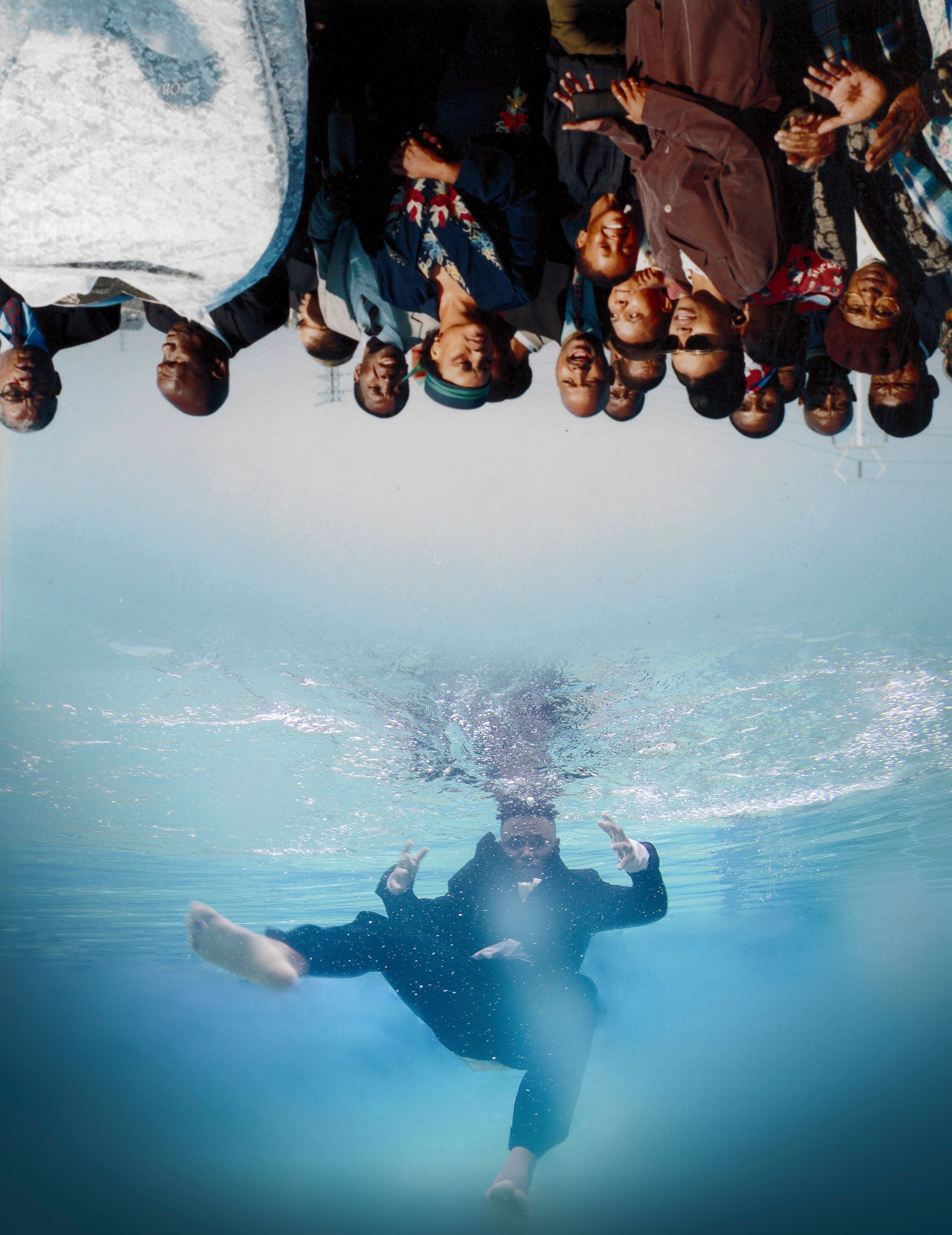 An inverted scene of many Black people on land overlooks a Black man in a suit sinking into clear blue water.