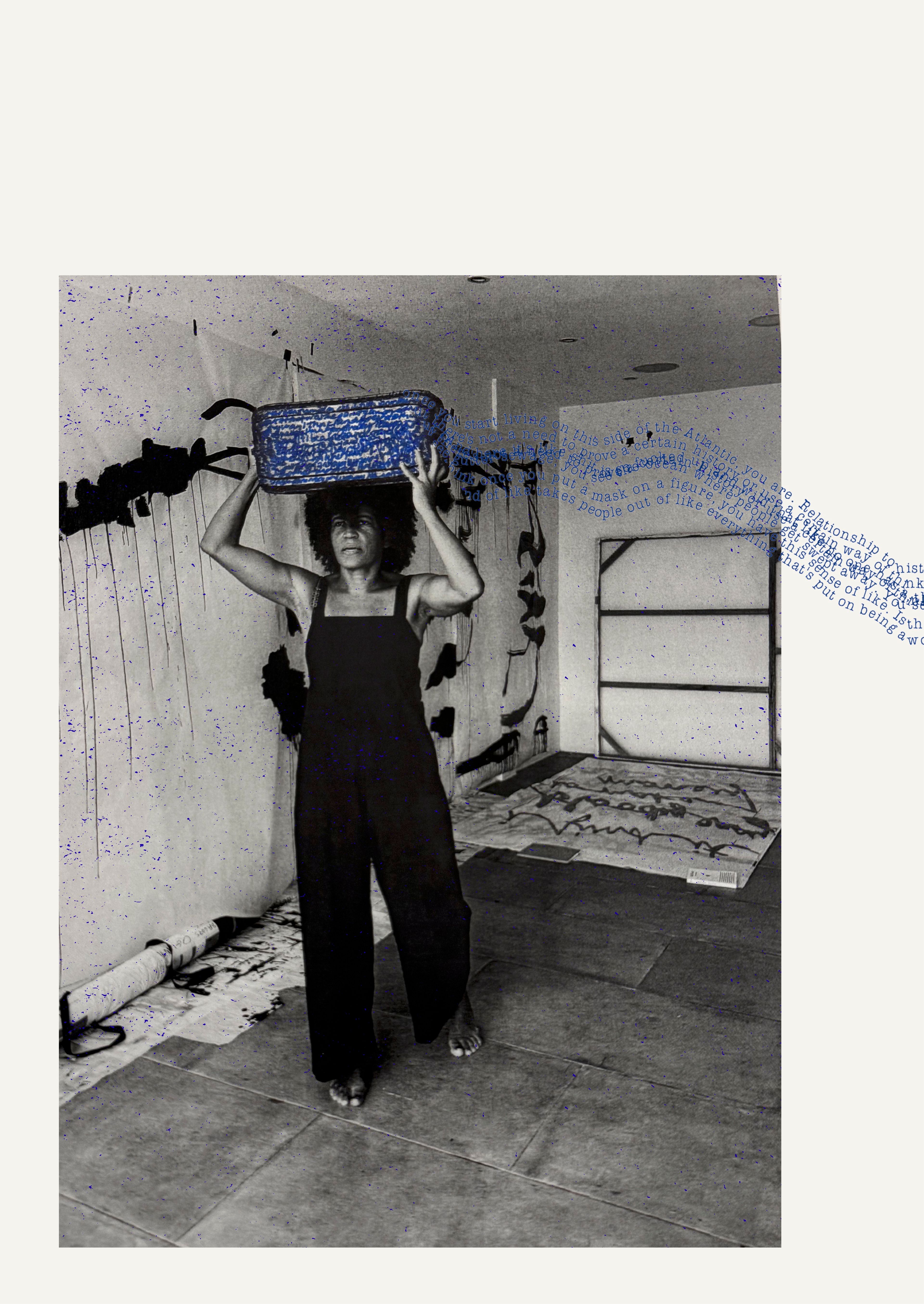 A barefoot Black woman in a black jumpsuit balances a blue woven basket on her head in a paint-splattered studio. The black and white photo has blue text overlay and speckles.