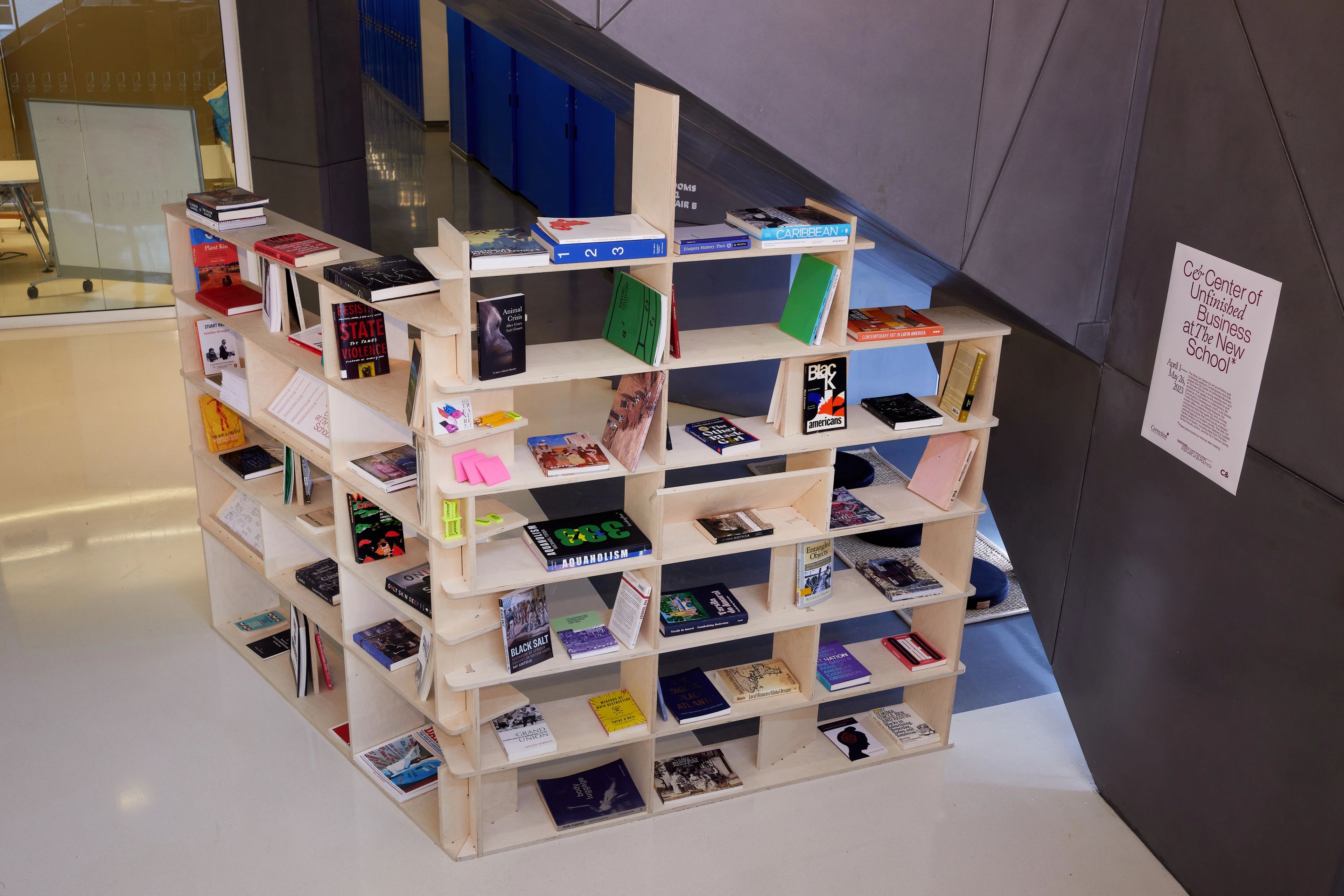 A unique interlocking wooden bookshelf filled with books stands in a modern interior space.