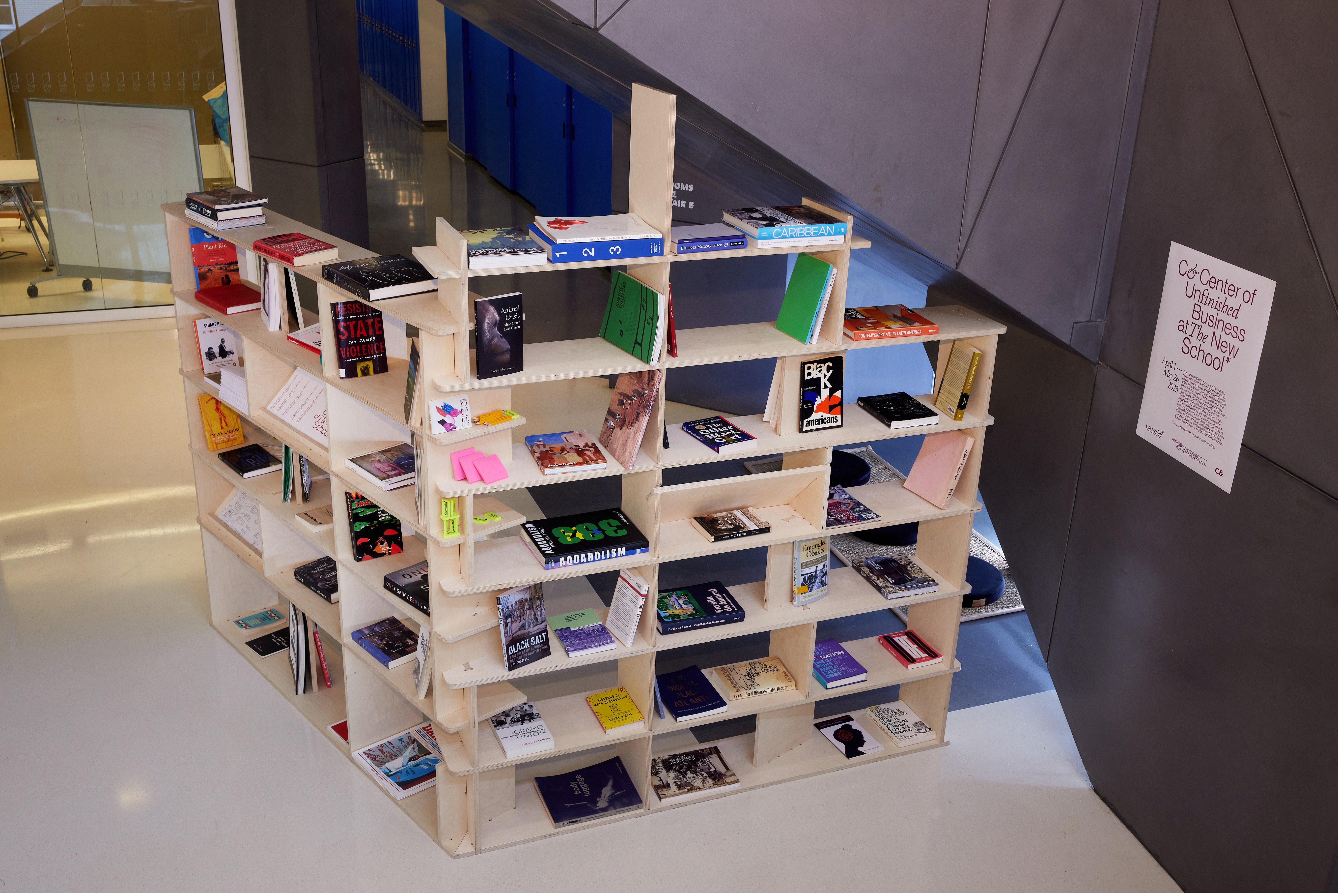 A unique interlocking wooden bookshelf filled with books stands in a modern interior space.