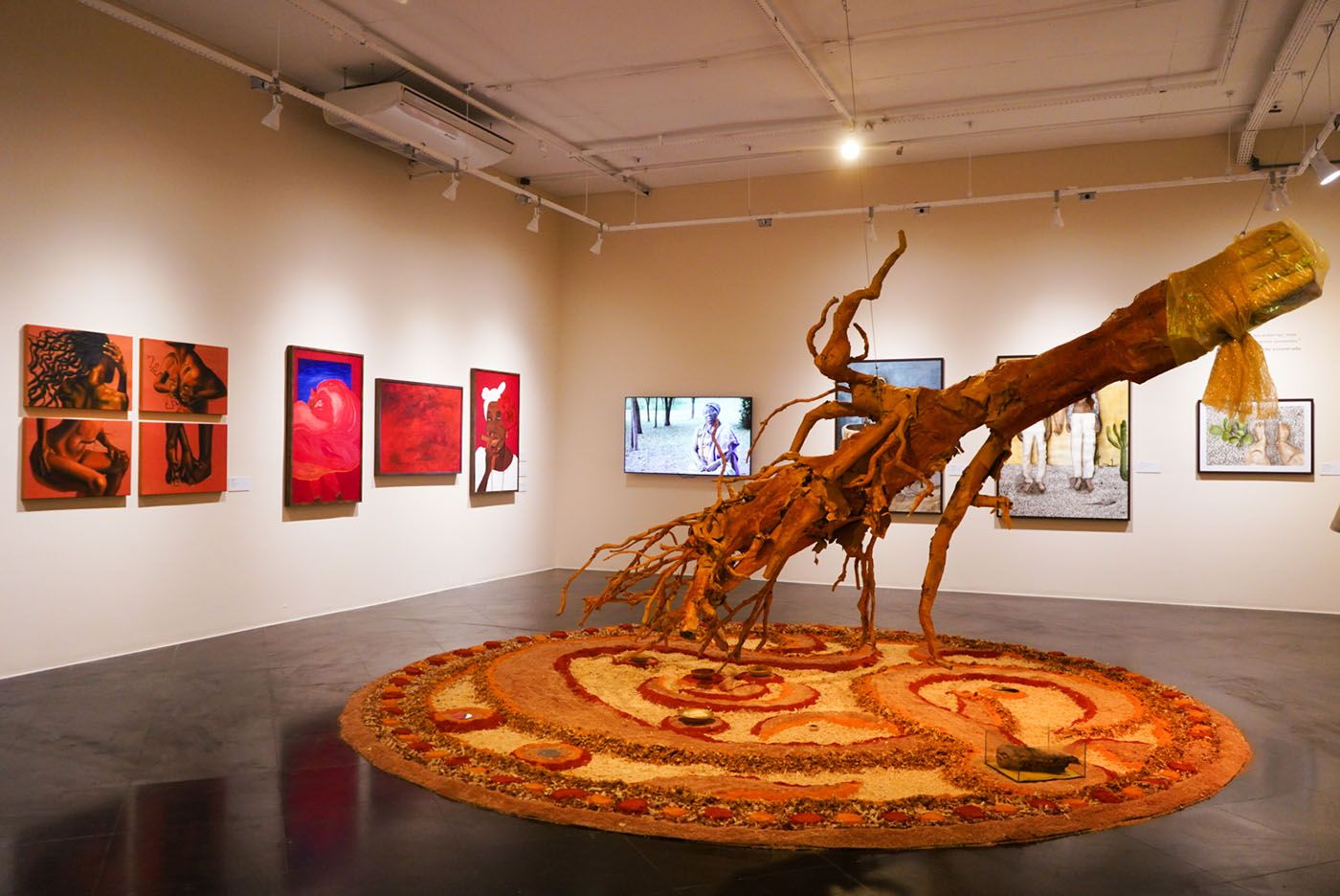 Jeise Ekê de Lundu, “Quem Procura o que não Guardou quando encontra não Reconhece”, 2024. Installation. Cardboard tree, kraft paper roll, latex paint, geo-paint, organic varnish, insect shells and fabric, sawdust floor with ceramic plates, 10 m x 10 m x 4 m. Artist’s collection. Photo: Luan Teles / SecultBA