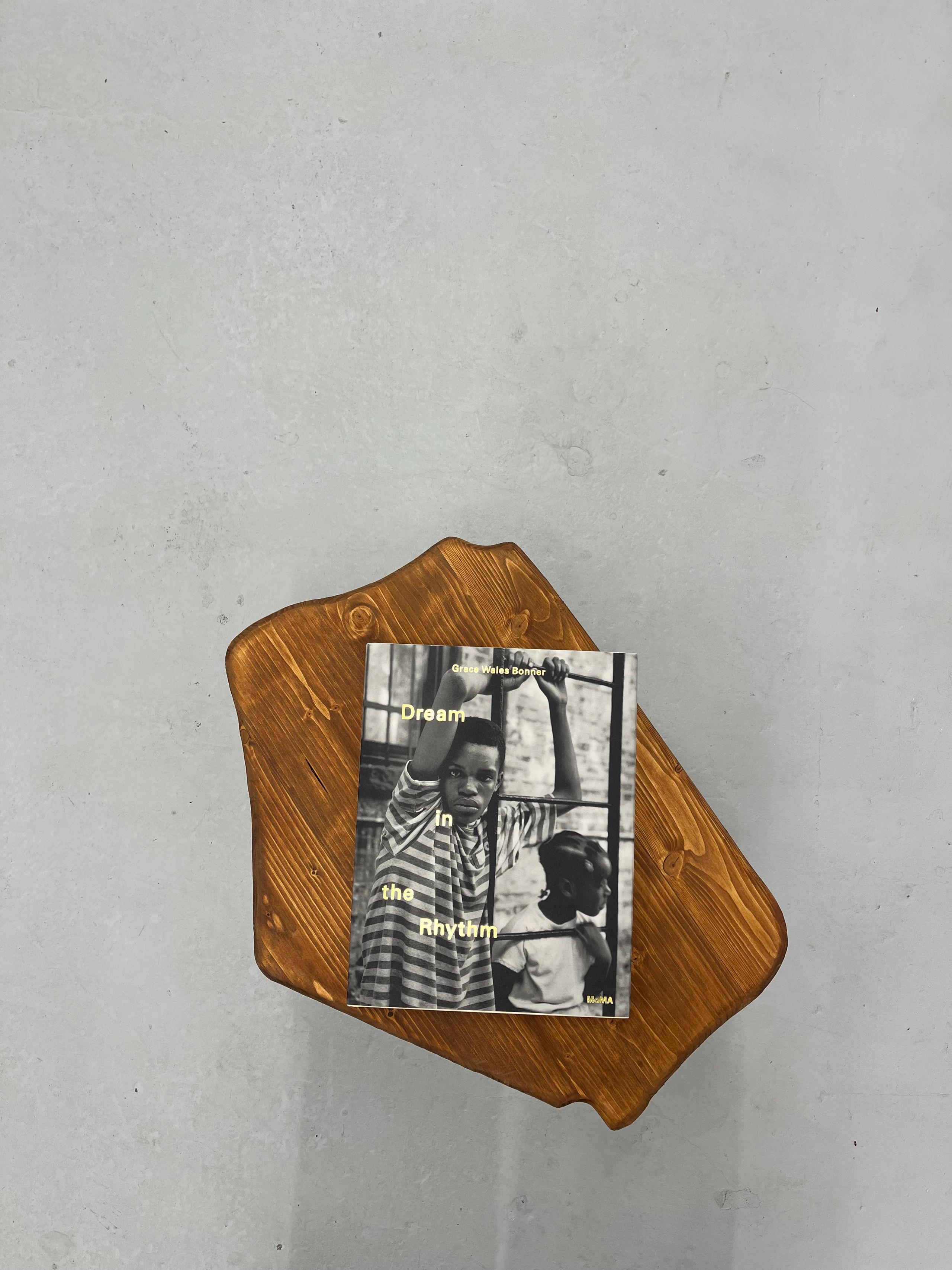 A book titled "Dream In the Rhythm" featuring a black and white cover photo of two children, resting on a live-edge wooden board against a gray textured background.