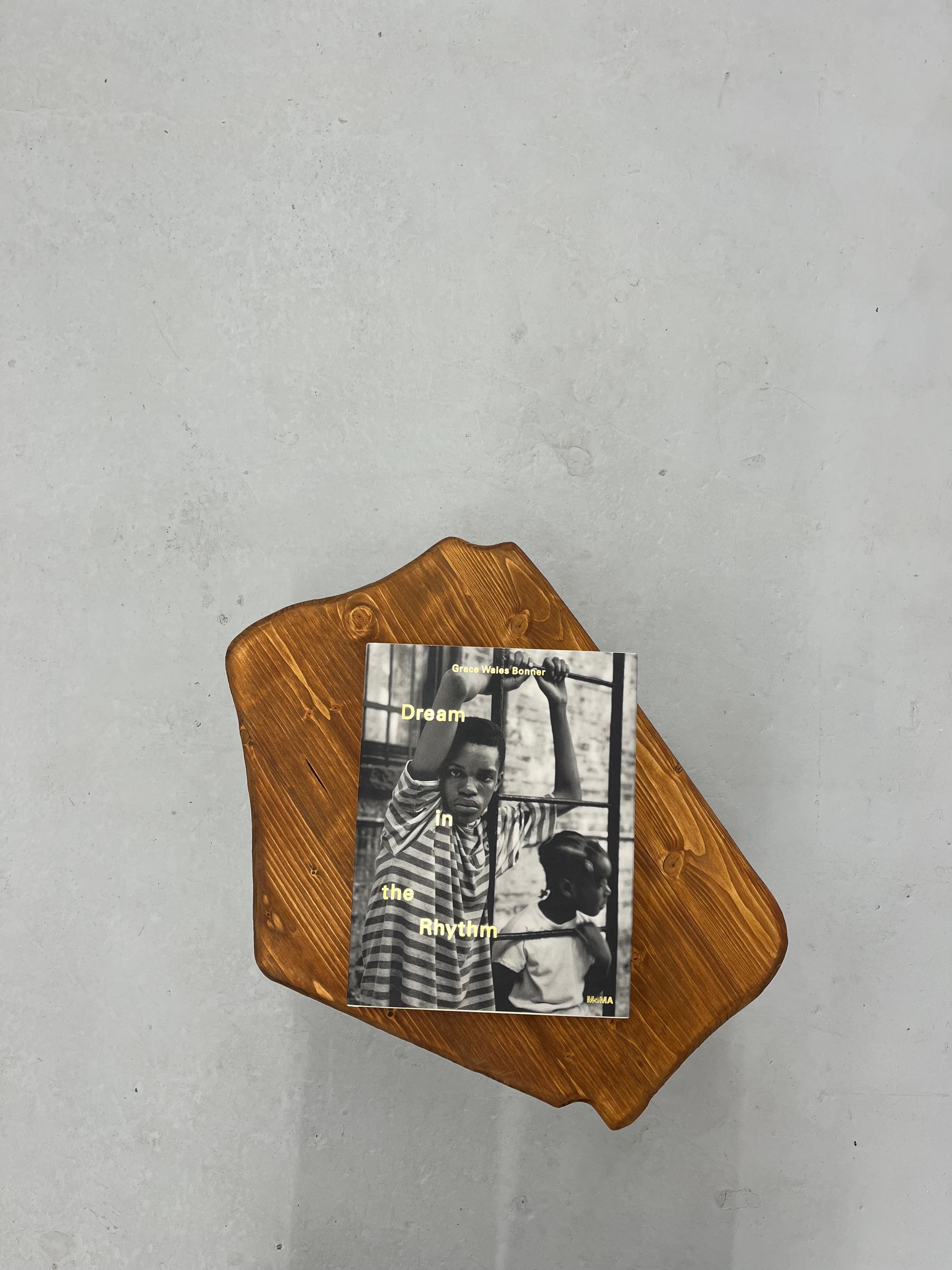 A book titled "Dream In the Rhythm" featuring a black and white cover photo of two children, resting on a live-edge wooden board against a gray textured background.