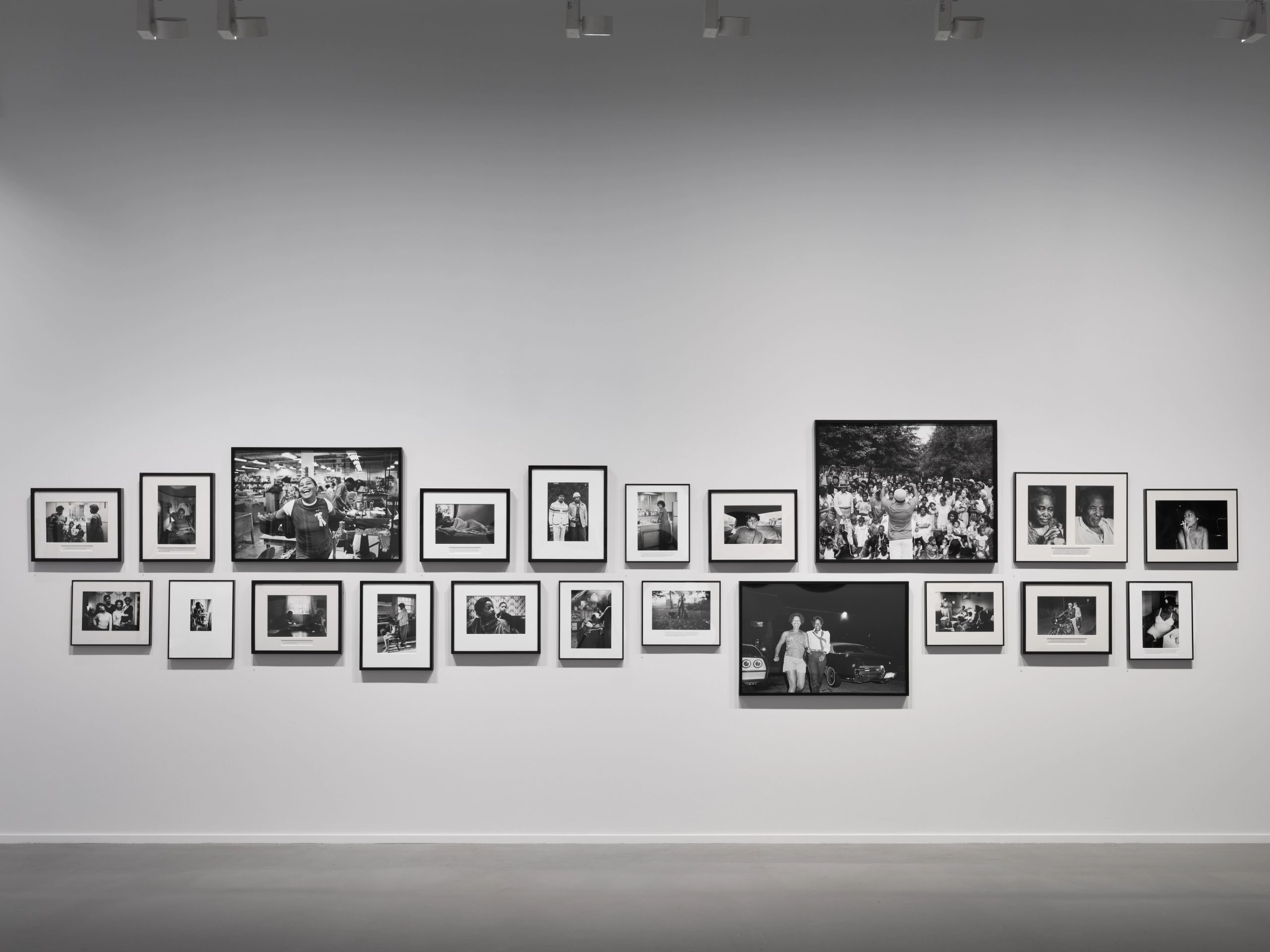 A gallery wall displaying two rows of framed black and white photographs of various scenes.