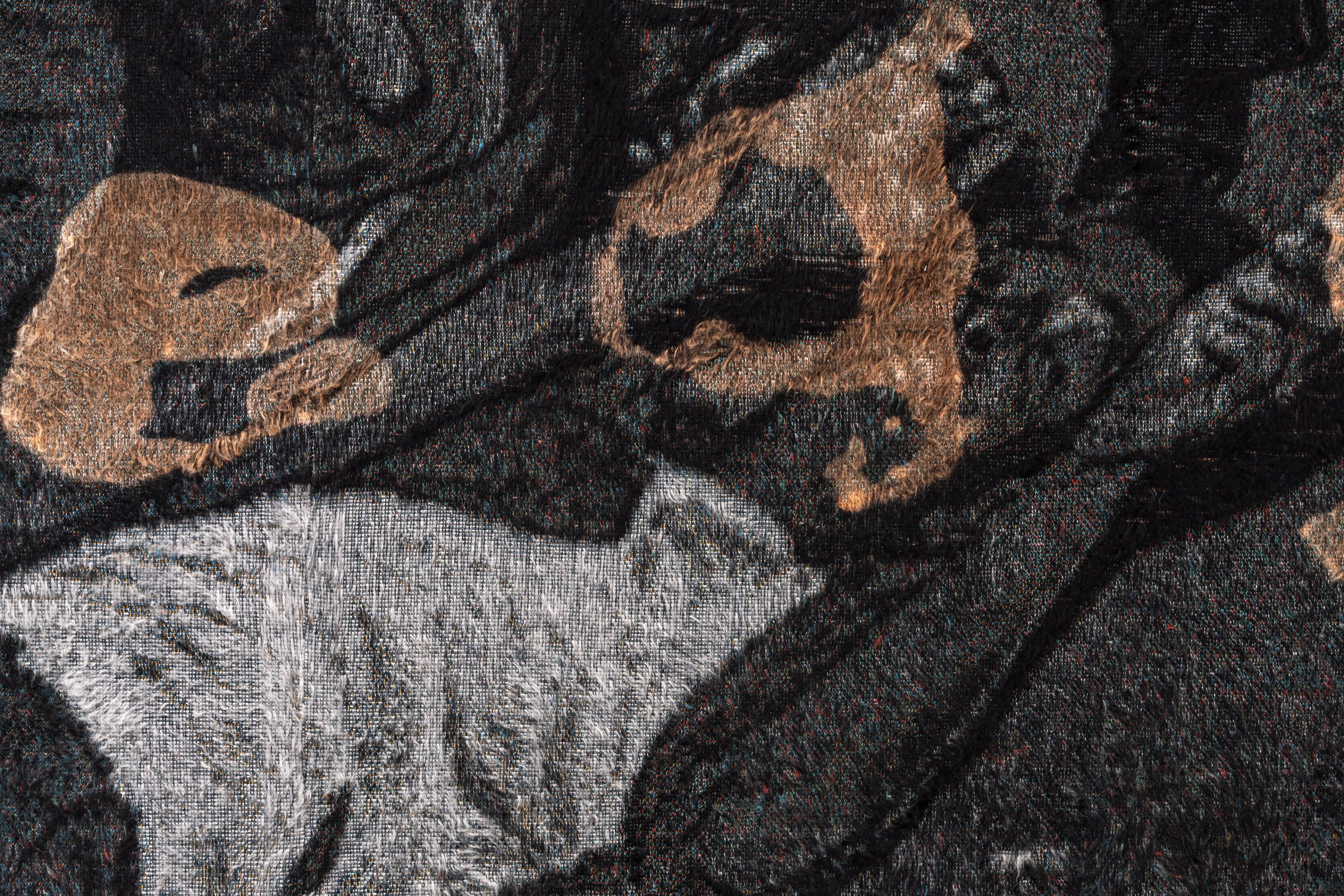 Close-up of a textured fabric showing a grey cat pattern and abstract golden shapes on a dark background.