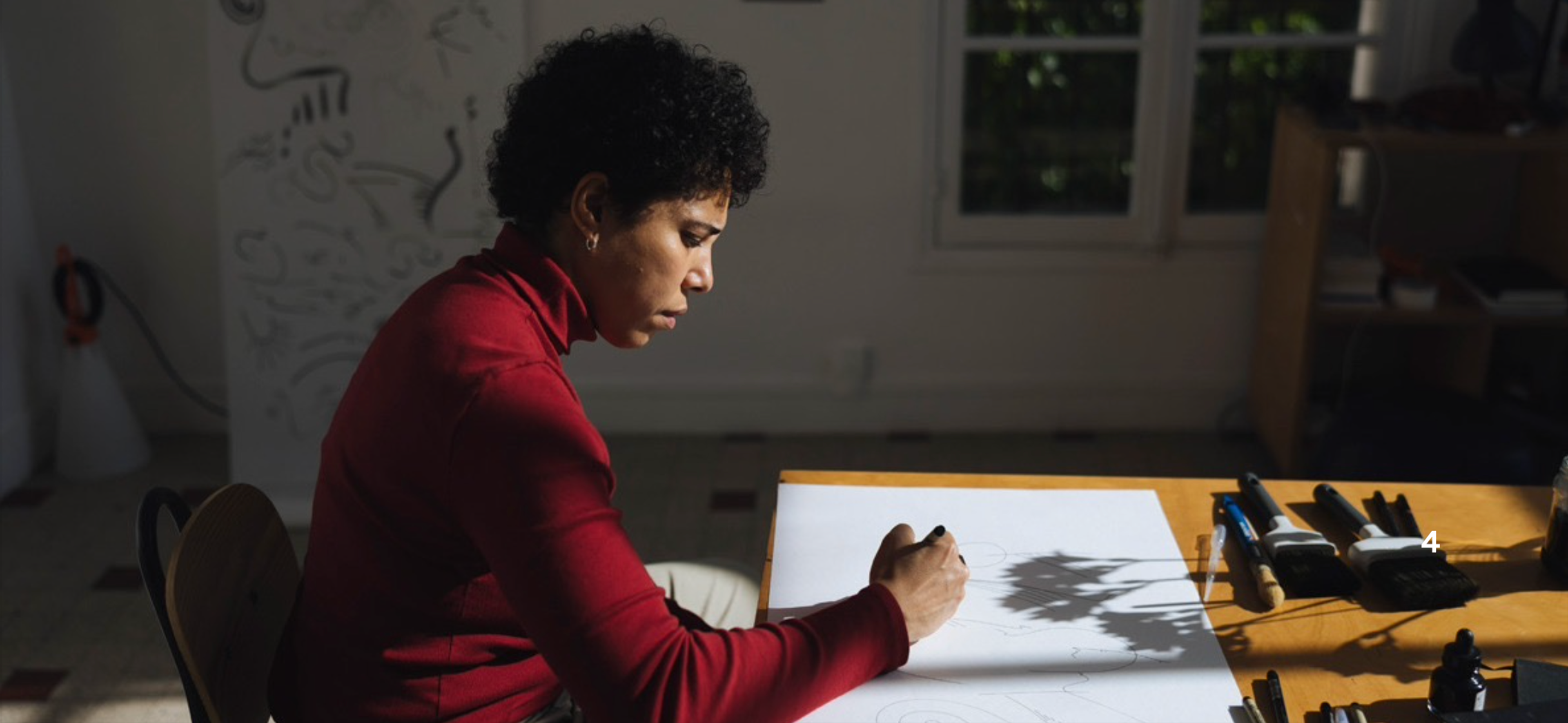 An artist in a red turtleneck draws at a sunlit desk in a promotional poster for a residency program in Paris.