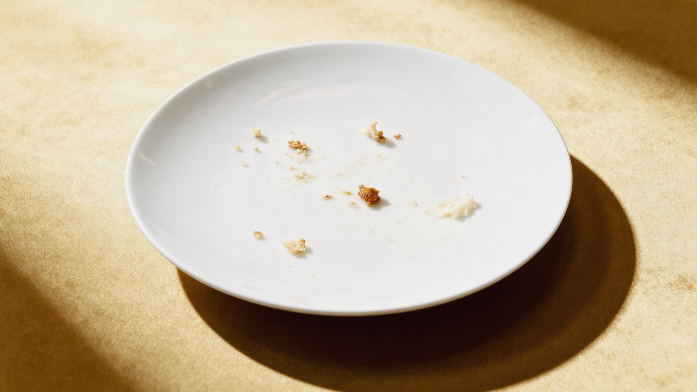 White plate with crumbs on a gold background.