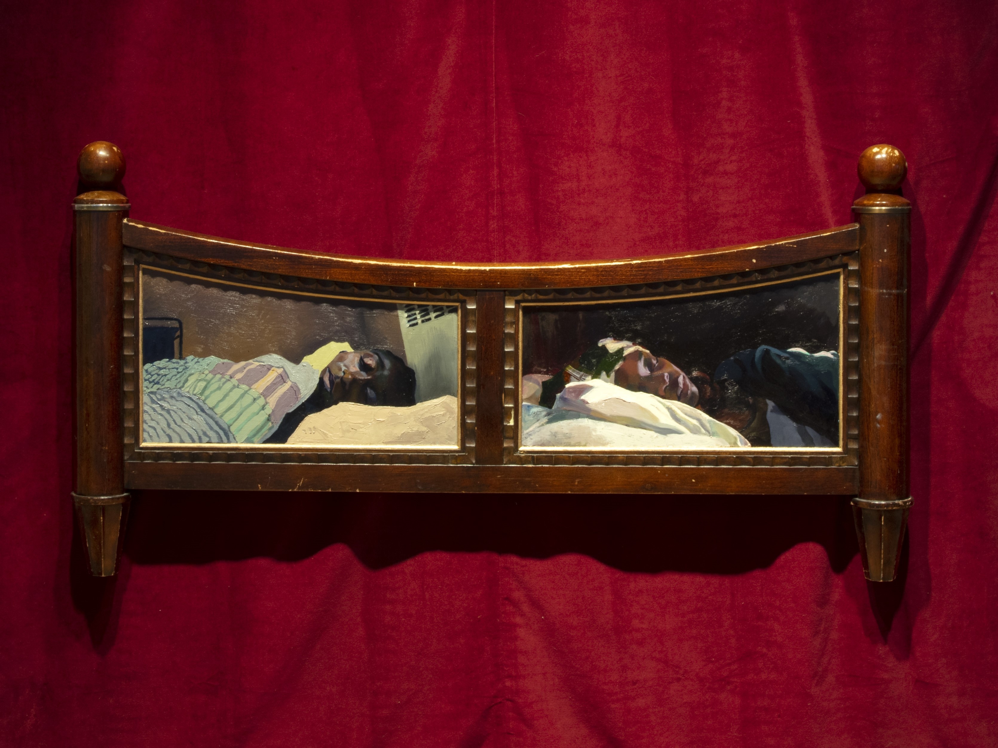 A carved wooden headboard featuring two paintings of individuals lying in bed, set against a deep red draped background.