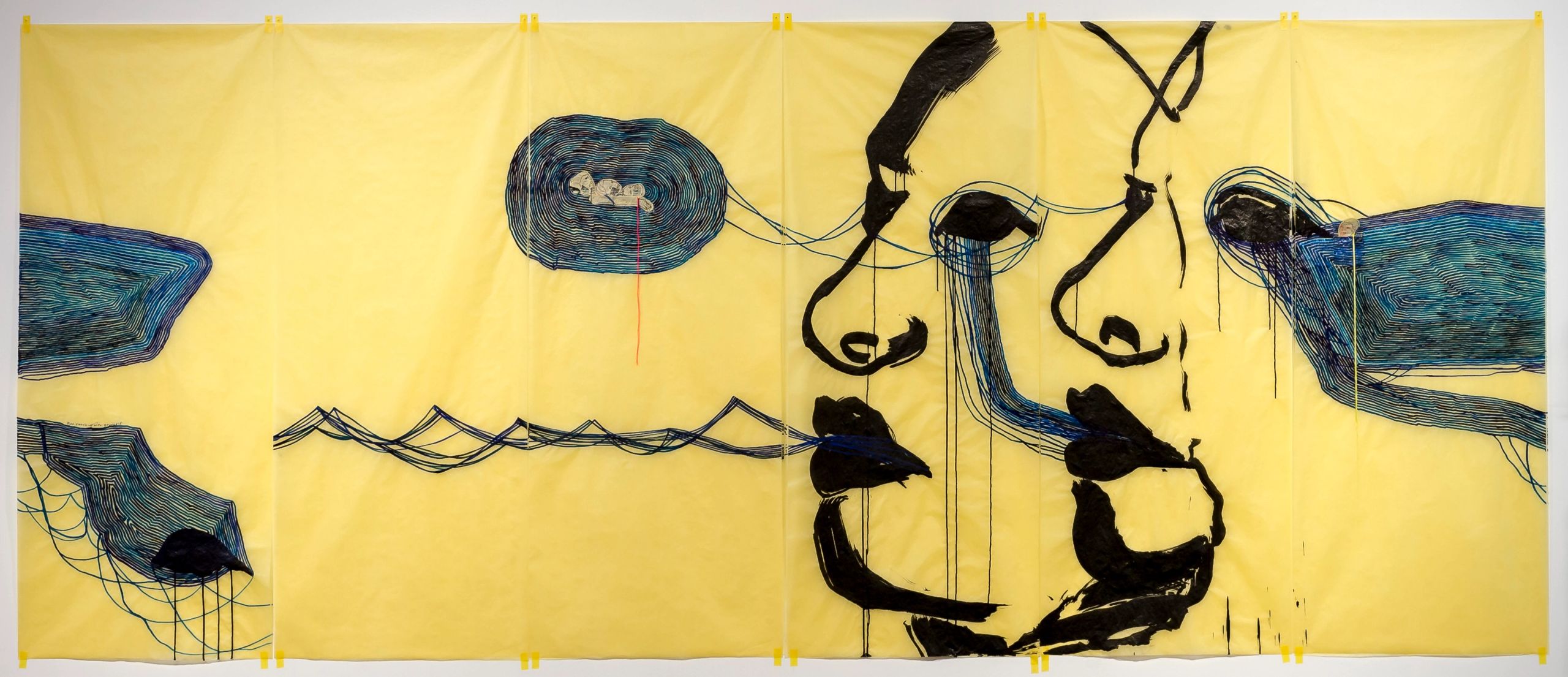 Abstract artwork: bold black distorted faces and figures on yellow fabric, with textured blue shapes and flowing lines.