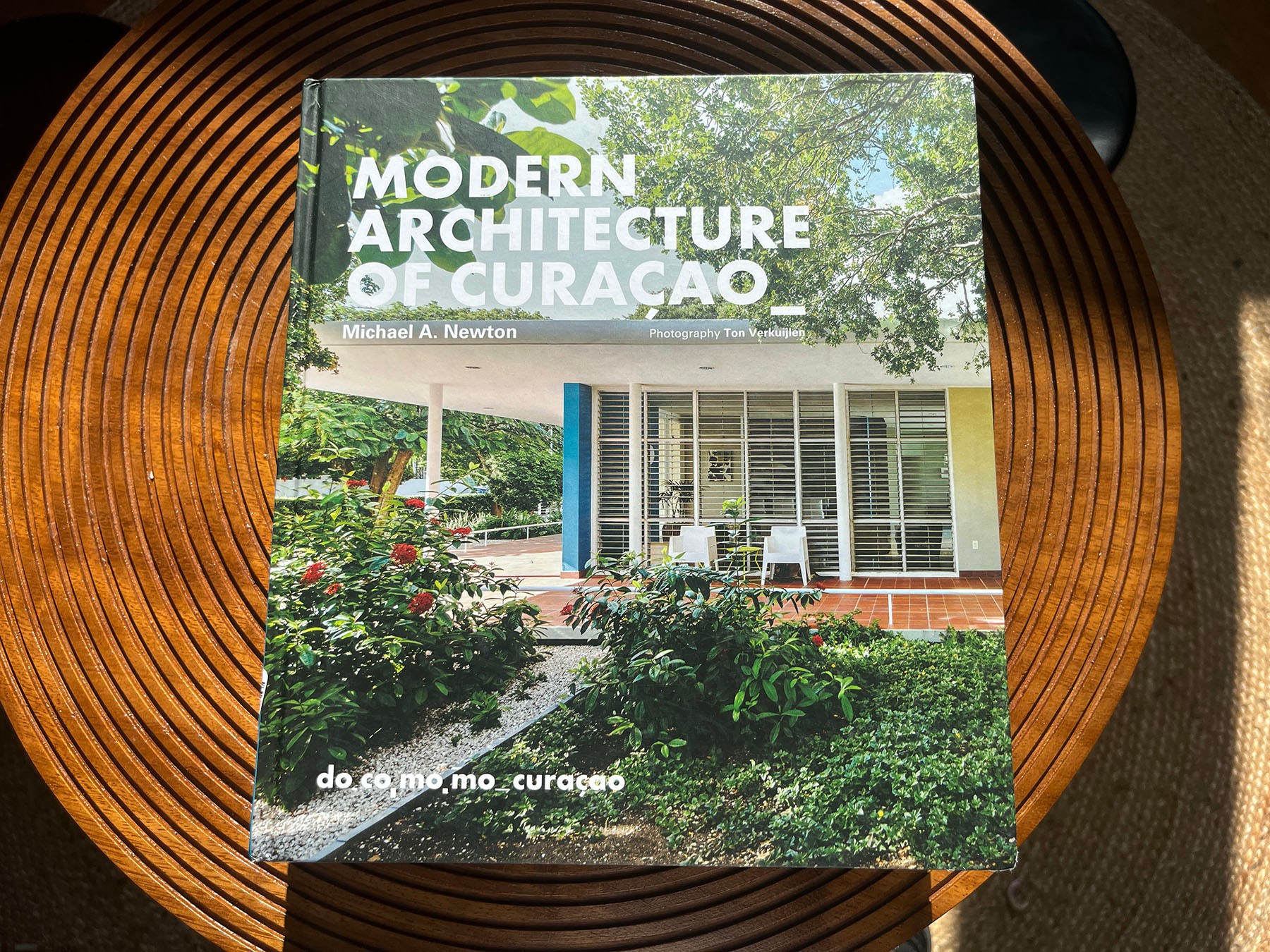 Book titled "Modern Architecture of Curacao" on a wooden slatted table.