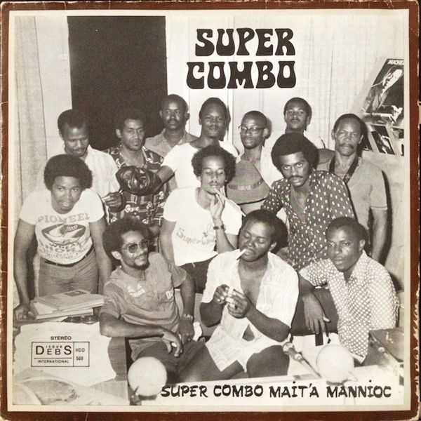 Black and white album cover for Super Combo's "Mait'a Mannioc", showing a large group of men in a relaxed pose, with some smoking.