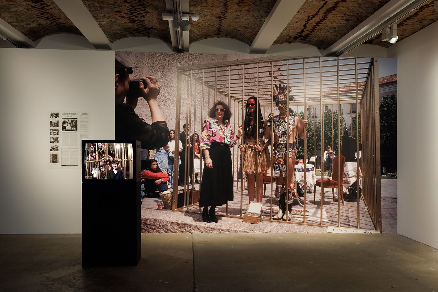 Archive material of: Coco Fusco, Two Undiscovered Amerindians Visit the West, 1992-1994. Courtesy the artist (back); Coco Fusco with Paula Heredia, The Couple in the Cage: A Guatinaui Odyssey, 1993 (front). Installation view of the exhibition “Coco Fusco – Tomorrow, I Will Become an Island” at KW Institute for Contemporary Art, Berlin 2023; Photo: Frank Sperling