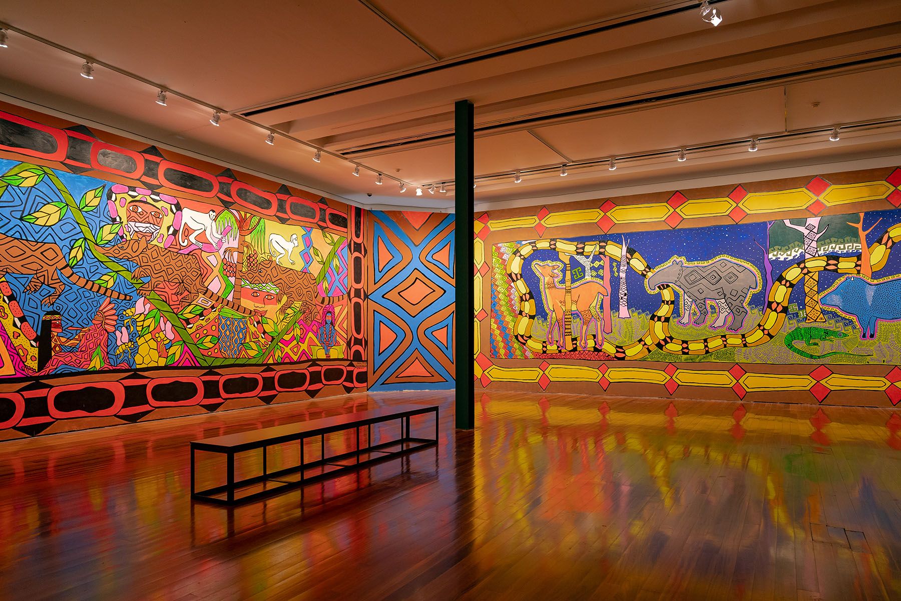 Large, vibrant murals depicting stylized animals and intricate patterns fill an art gallery.