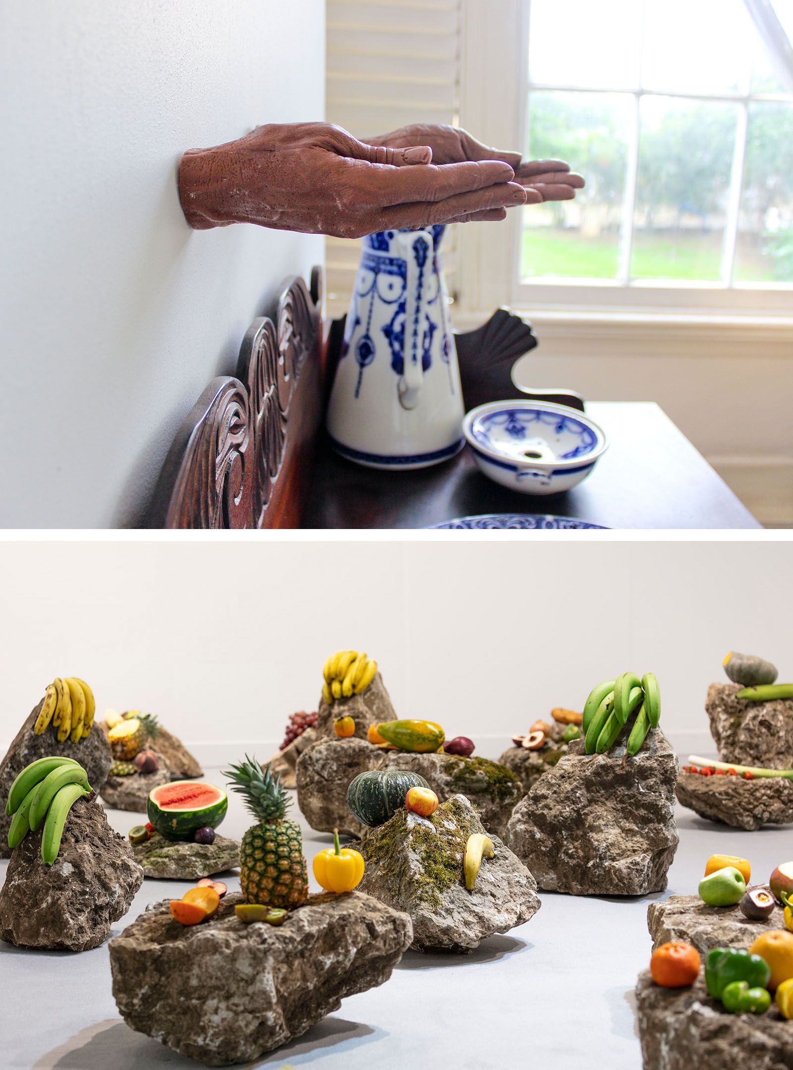 A diptych: above, hands extend from a wall over a table with blue and white pottery; below, an art installation of fruits on rocks.