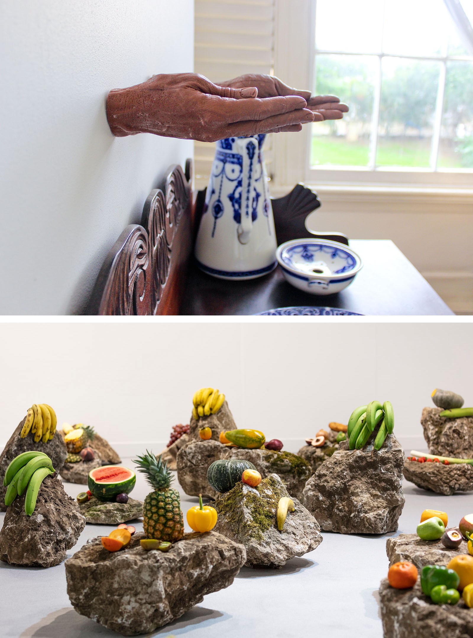 A diptych: above, hands extend from a wall over a table with blue and white pottery; below, an art installation of fruits on rocks.