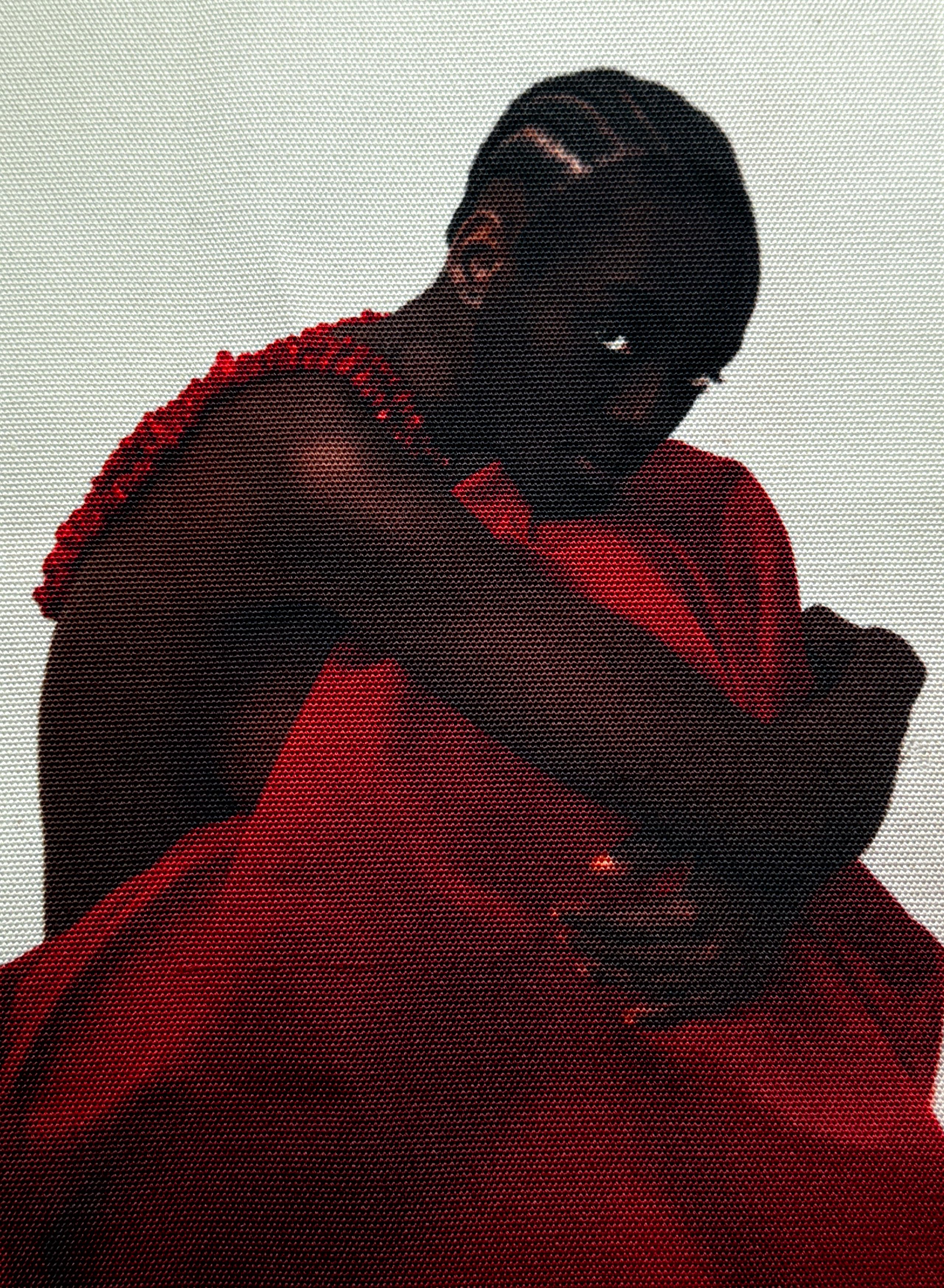 A dark-skinned person in a ruffled red top and draped red fabric, huddled with one eye peering from shadow.
