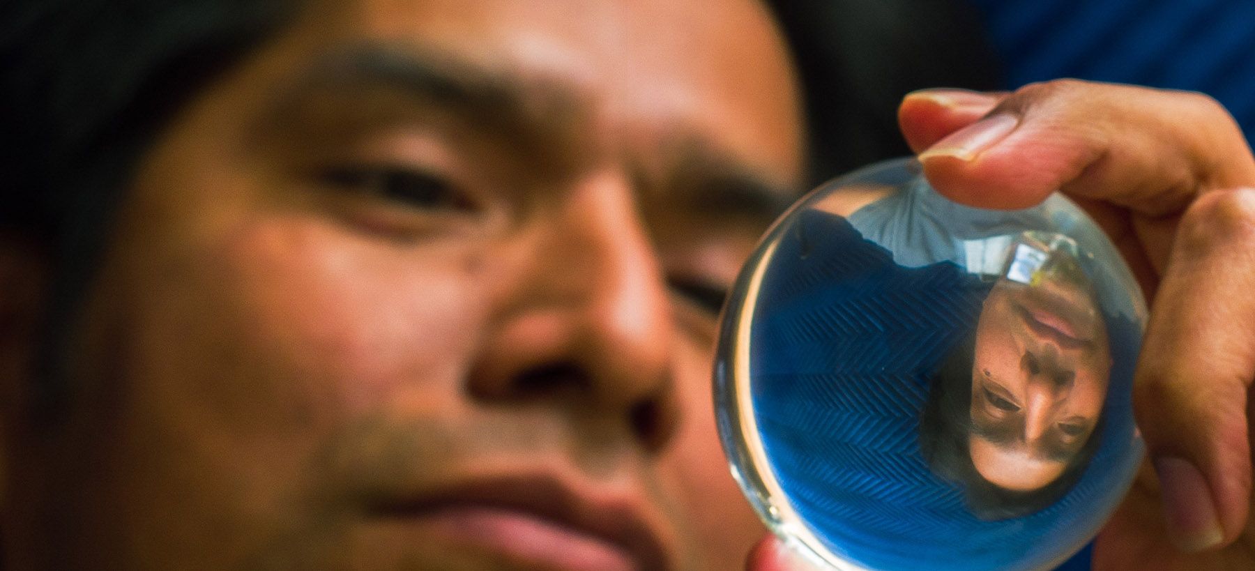 A person looking intently at their own upside-down reflection in a crystal ball.
