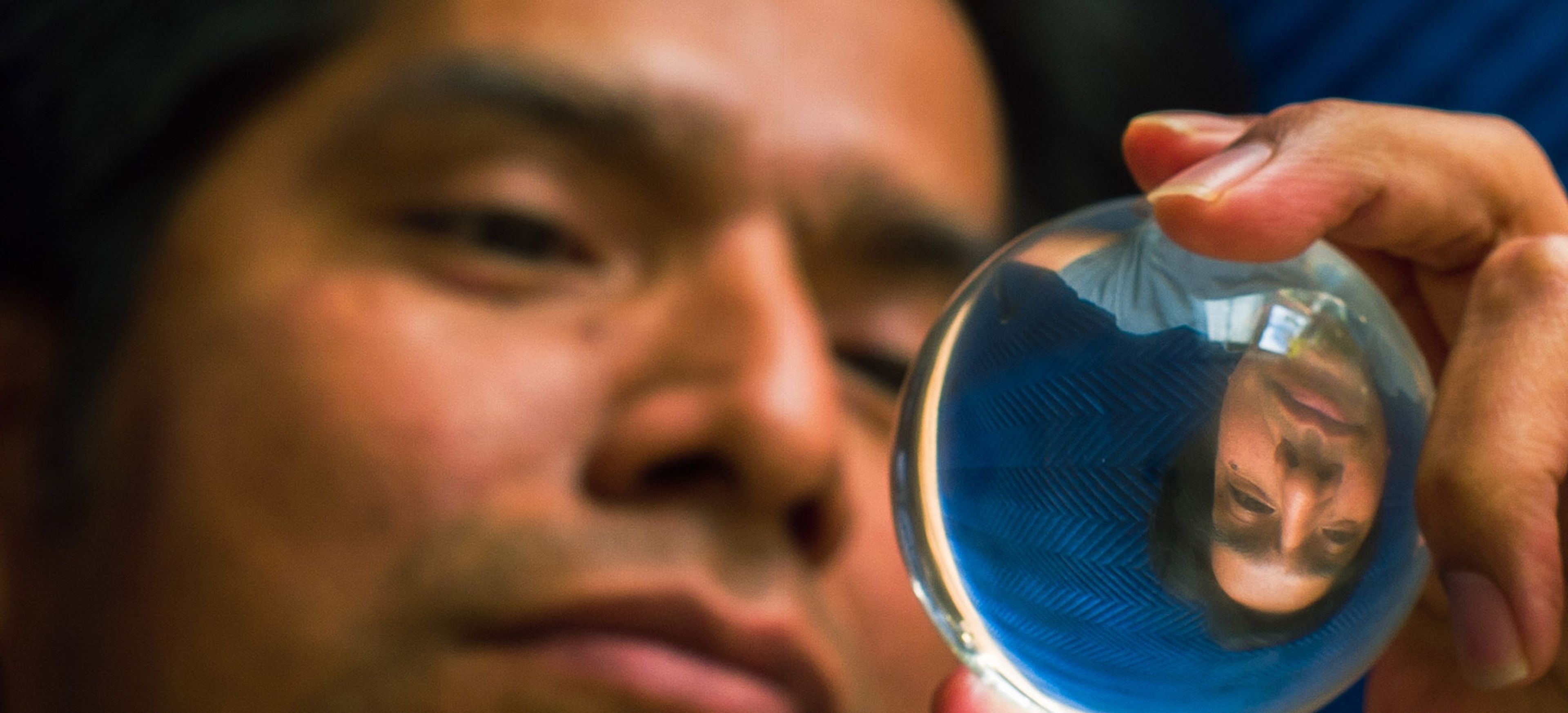 A person looking intently at their own upside-down reflection in a crystal ball.