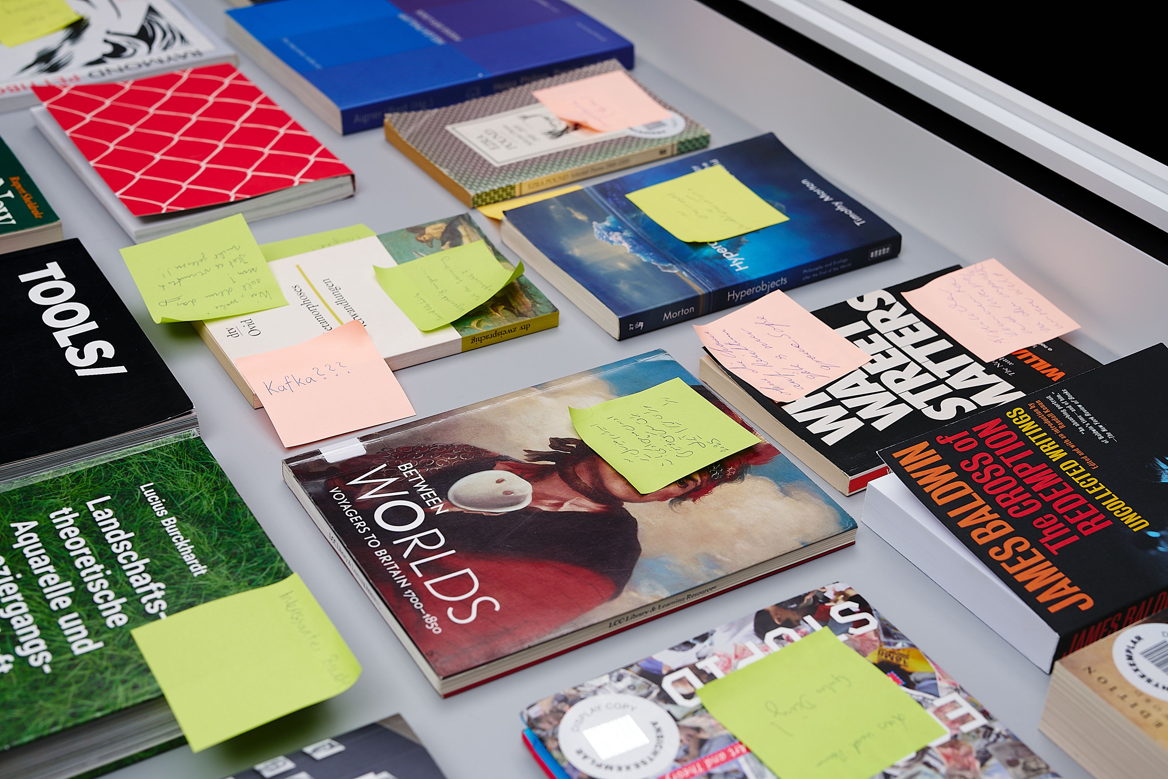 Books laid out on a surface, many with handwritten sticky notes.