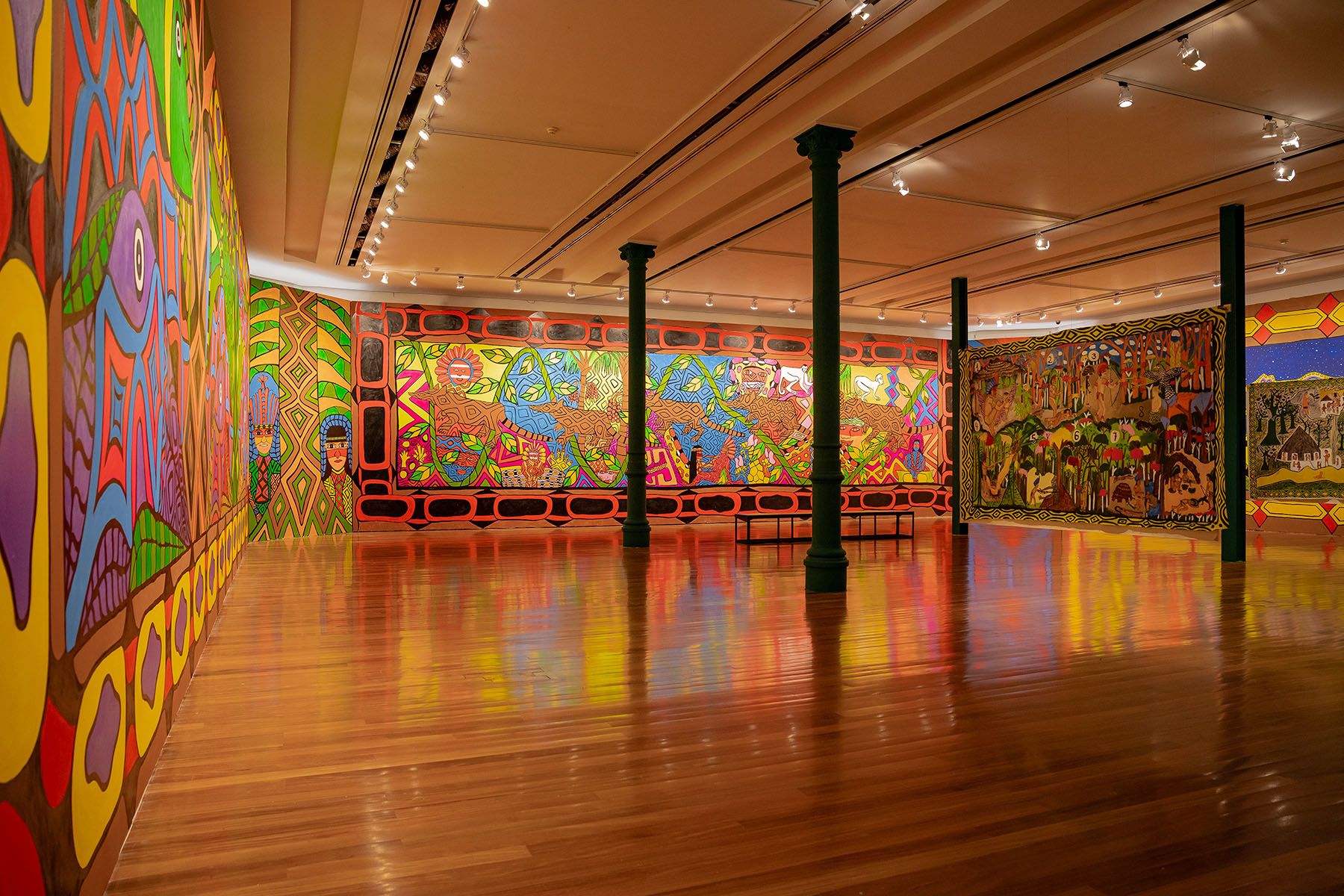 A vibrant art gallery features colorful murals and large tapestries on walls, with a polished wooden floor and dark green pillars.