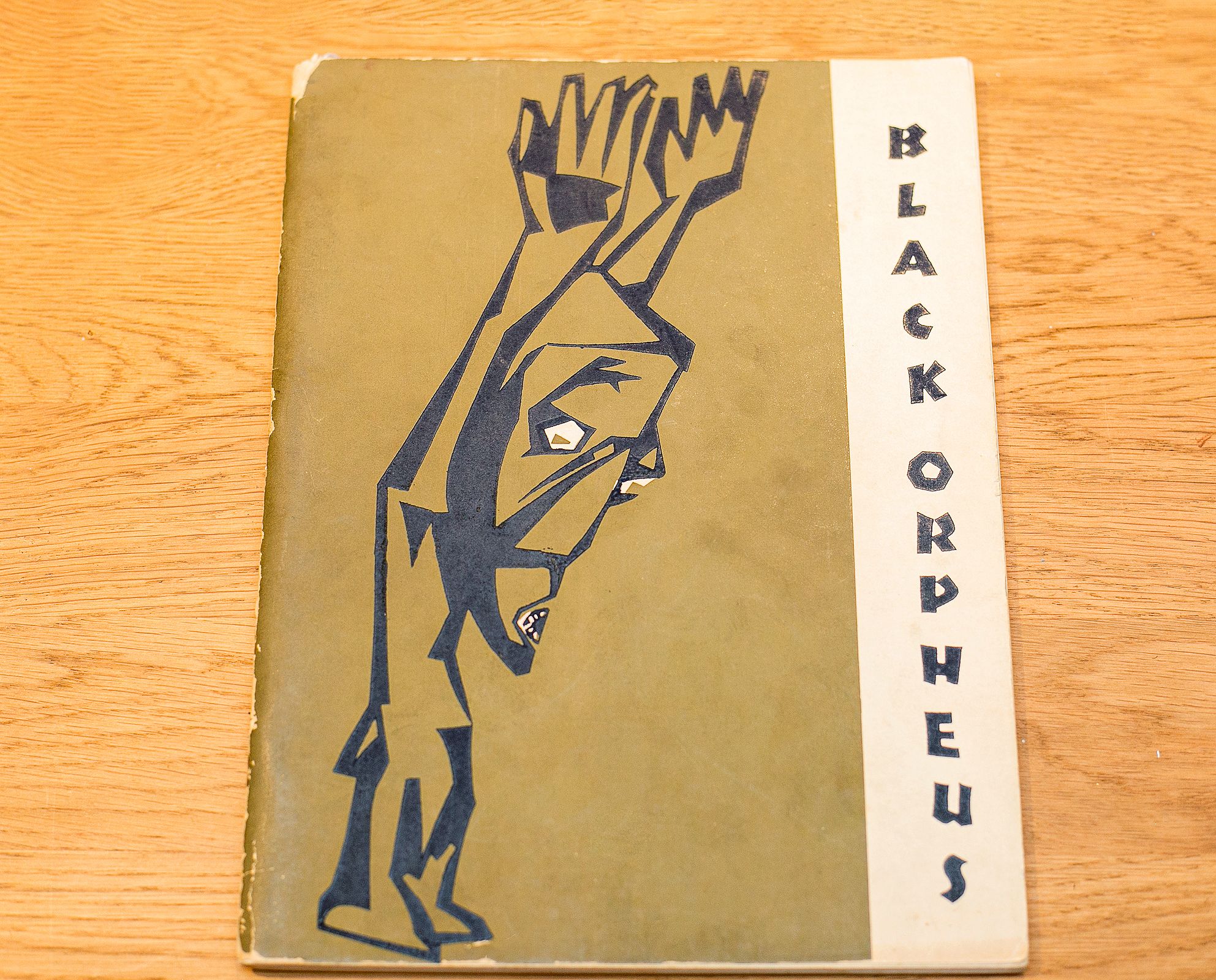 Worn cover of "BLACK ORPHEUS" journal with a dark, angular figure with raised arms on an olive background.