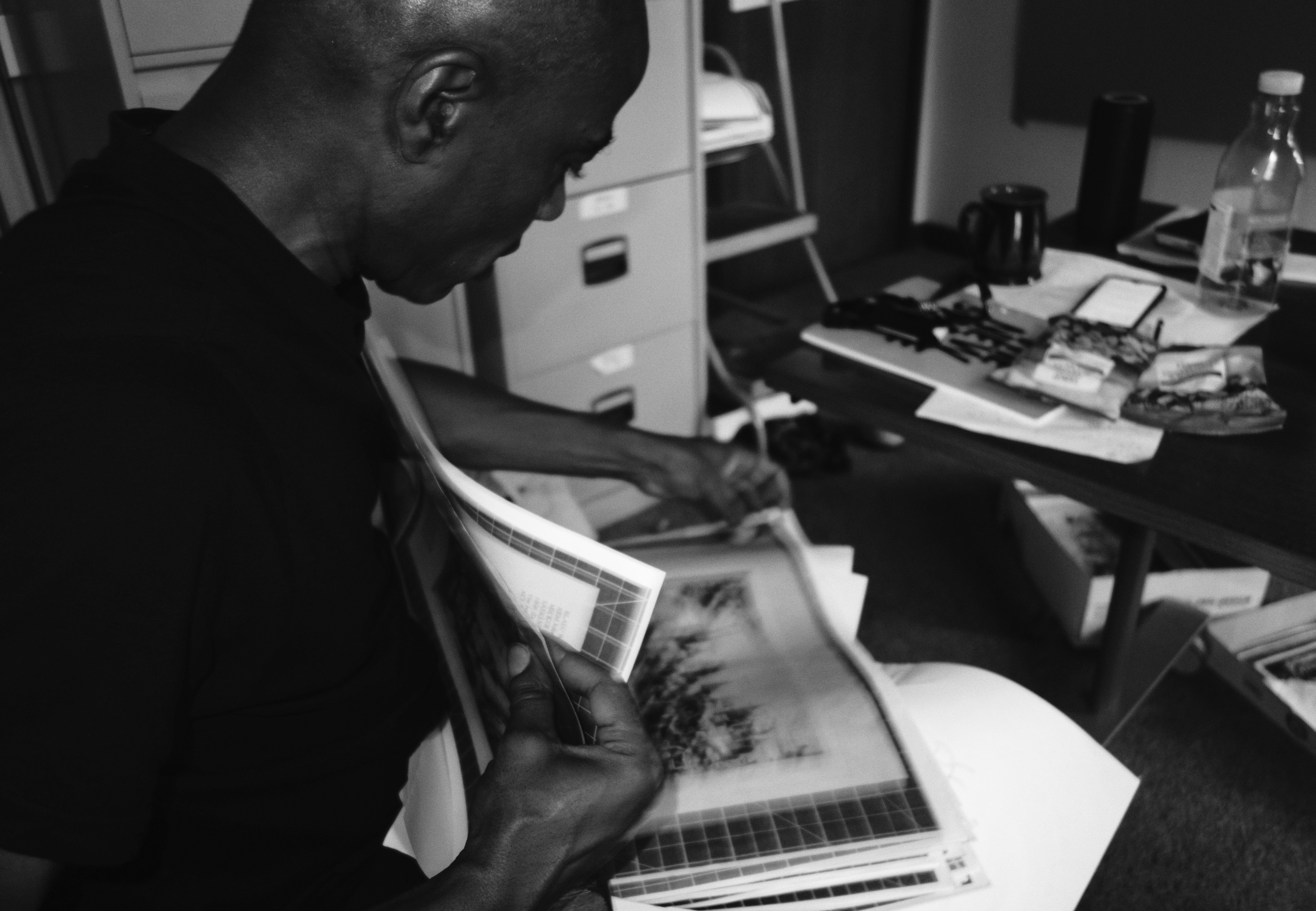 A man reviews black and white prints in an office.