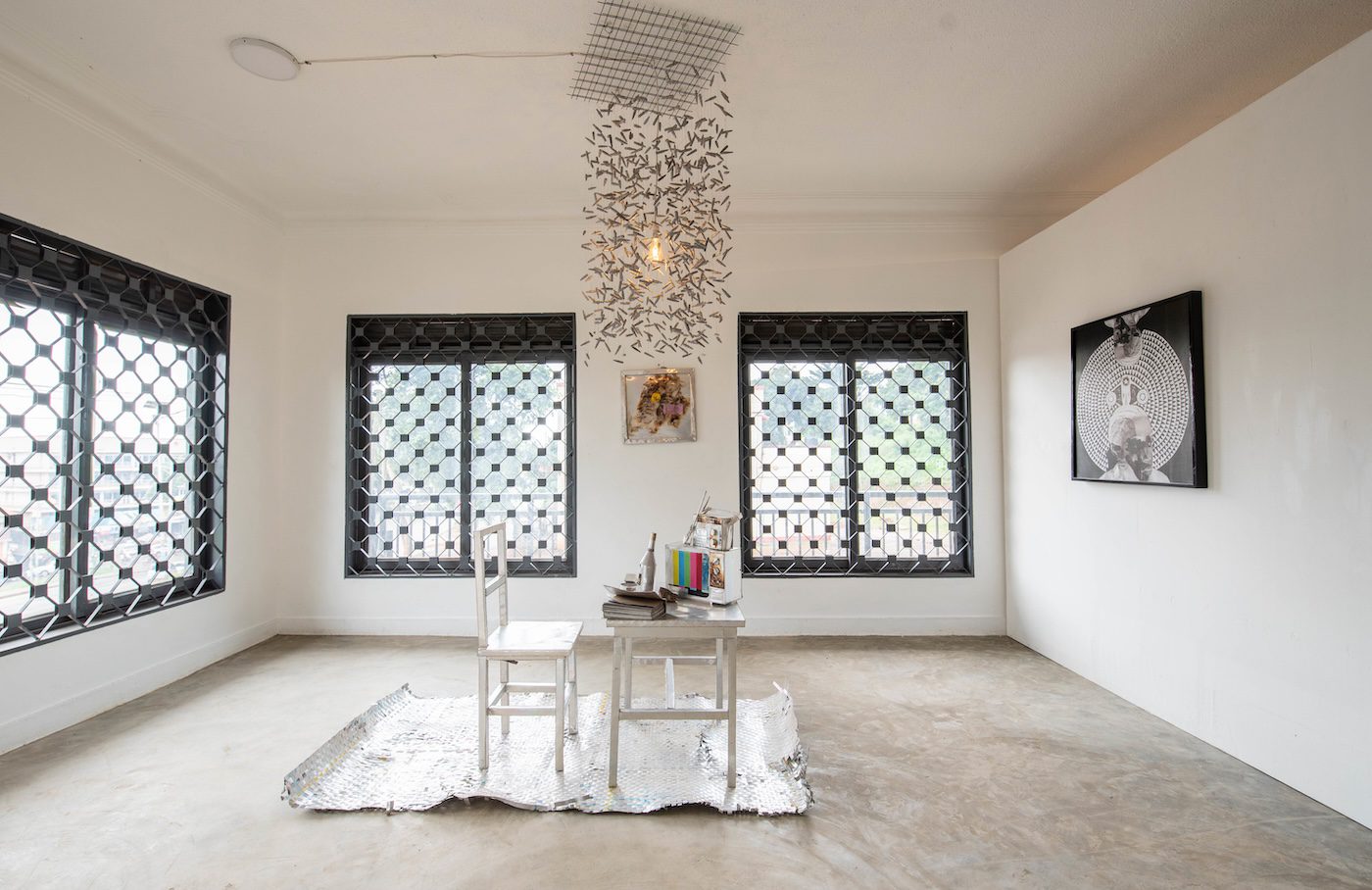 Odur Ronald, Muwawa, 2021, Installation of objects made of aluminum printing plates and copper wires, variable dimensions. Courtesy of the Artist and 32° EAST, and Ethel Aanyu, Opala, 2023, archival print on canvas, 85 x 81 cm at Silent Invasions: The Art of Material Hacking. Photo: Atiko Anthony