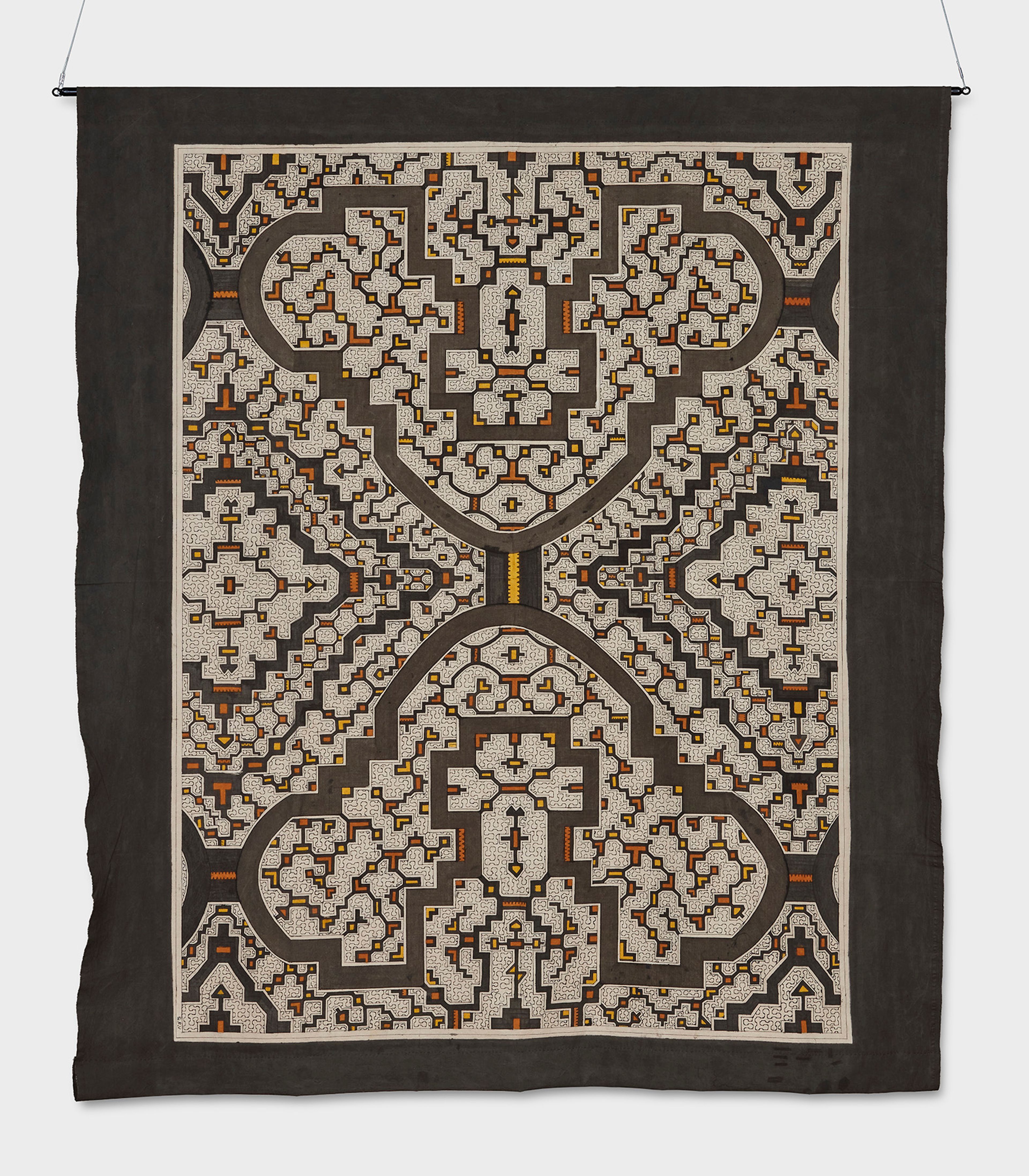 Hanging textile artwork featuring an intricate, symmetrical, maze-like pattern in brown, light grey, orange, and yellow.