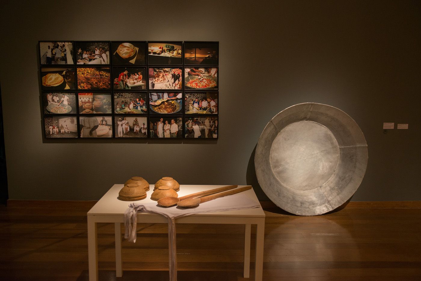 Ayrson Heráclito, Moqueca - The Atlantic Condor, 2002 - 2022, aluminum basin, table, 20 seats, plates, spoons and photographs, Photographs: 30 x 40 cm each; table: 120 x 85 x 80 cm); basin: 2m Ø. Artist's collection, Salvador, BA. Photo: Levi Fanan/Pinacoteca de São Paulo