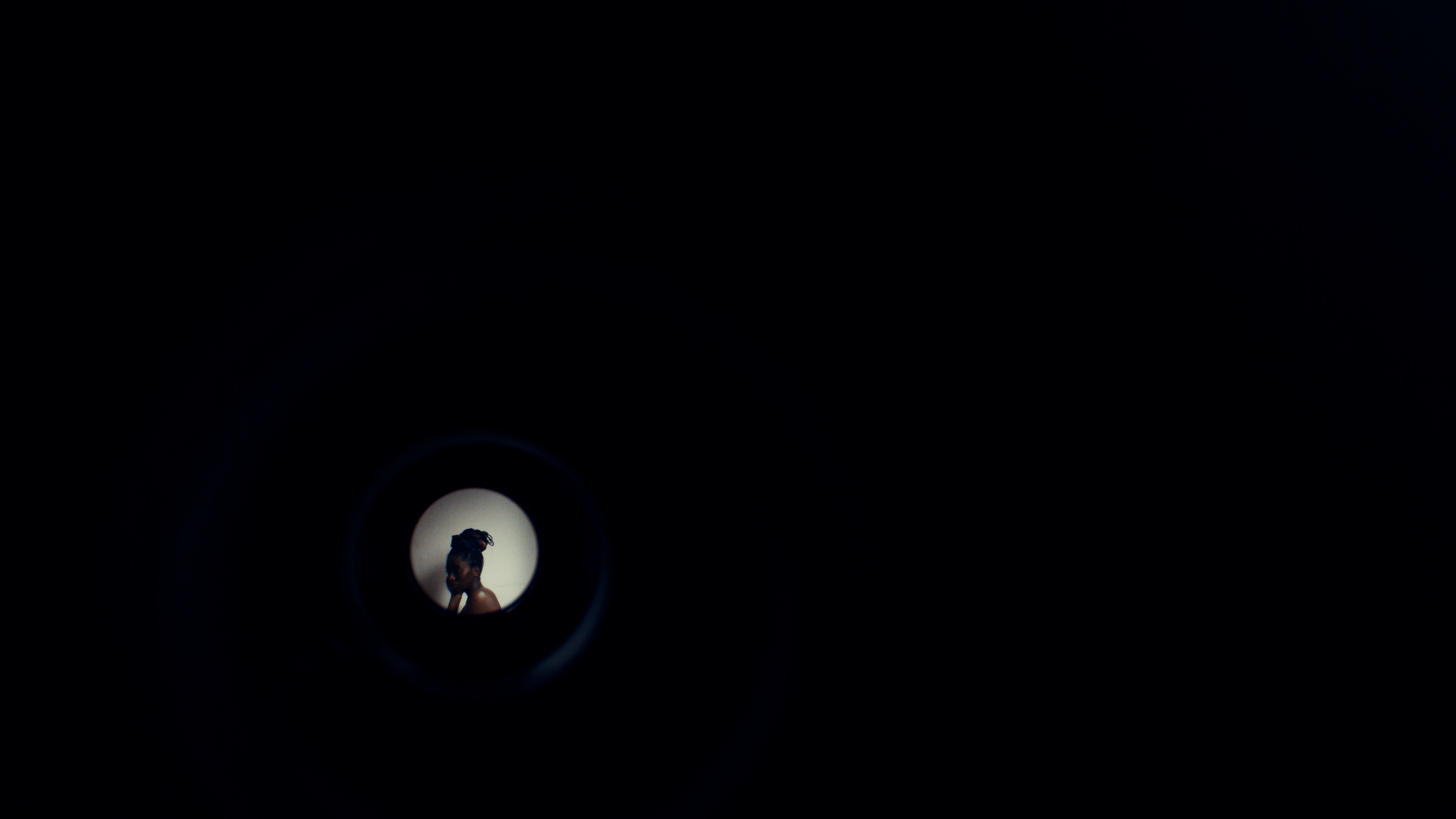 View through a peephole showing a person against a light background.