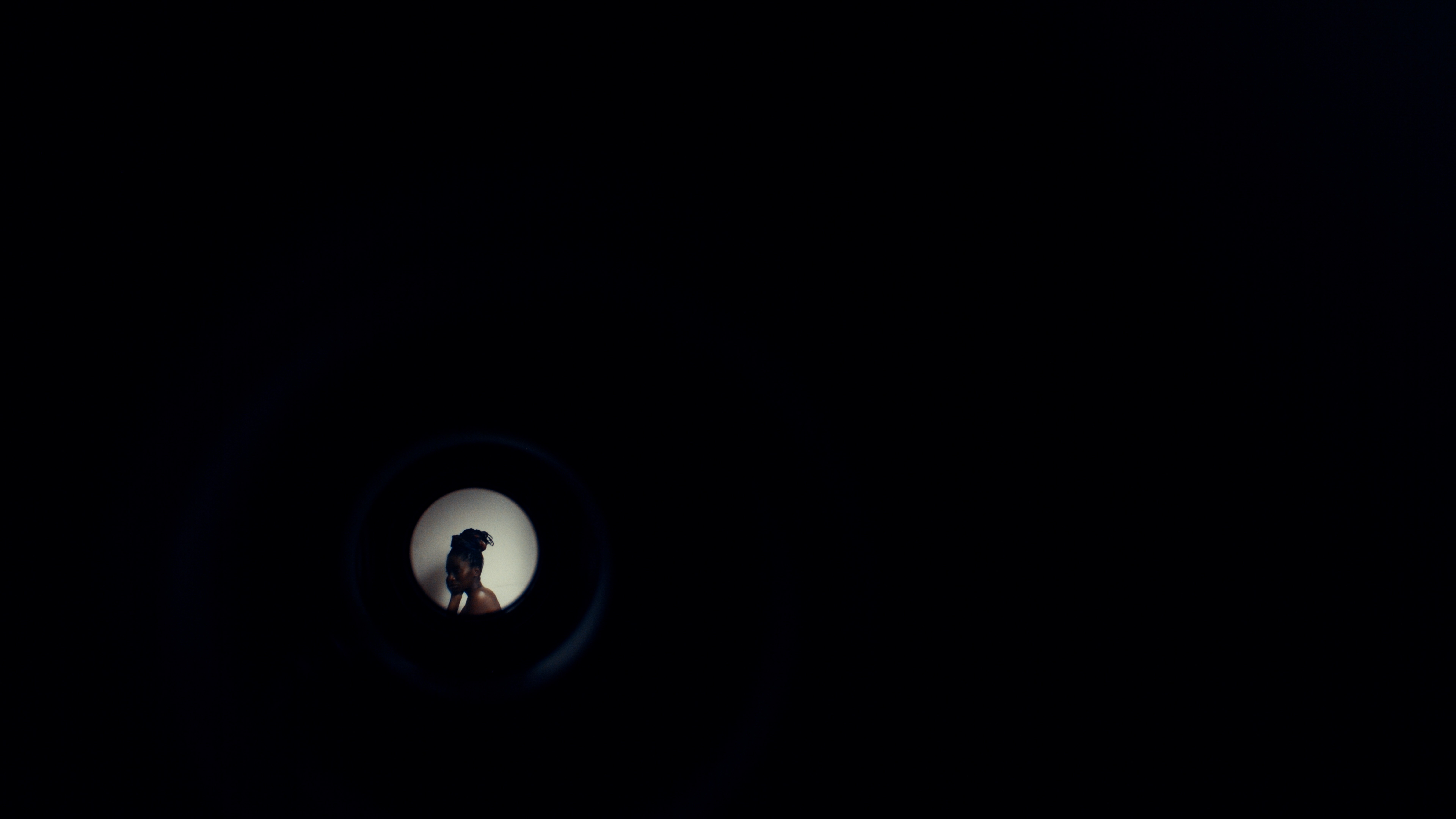 View through a peephole showing a person against a light background.
