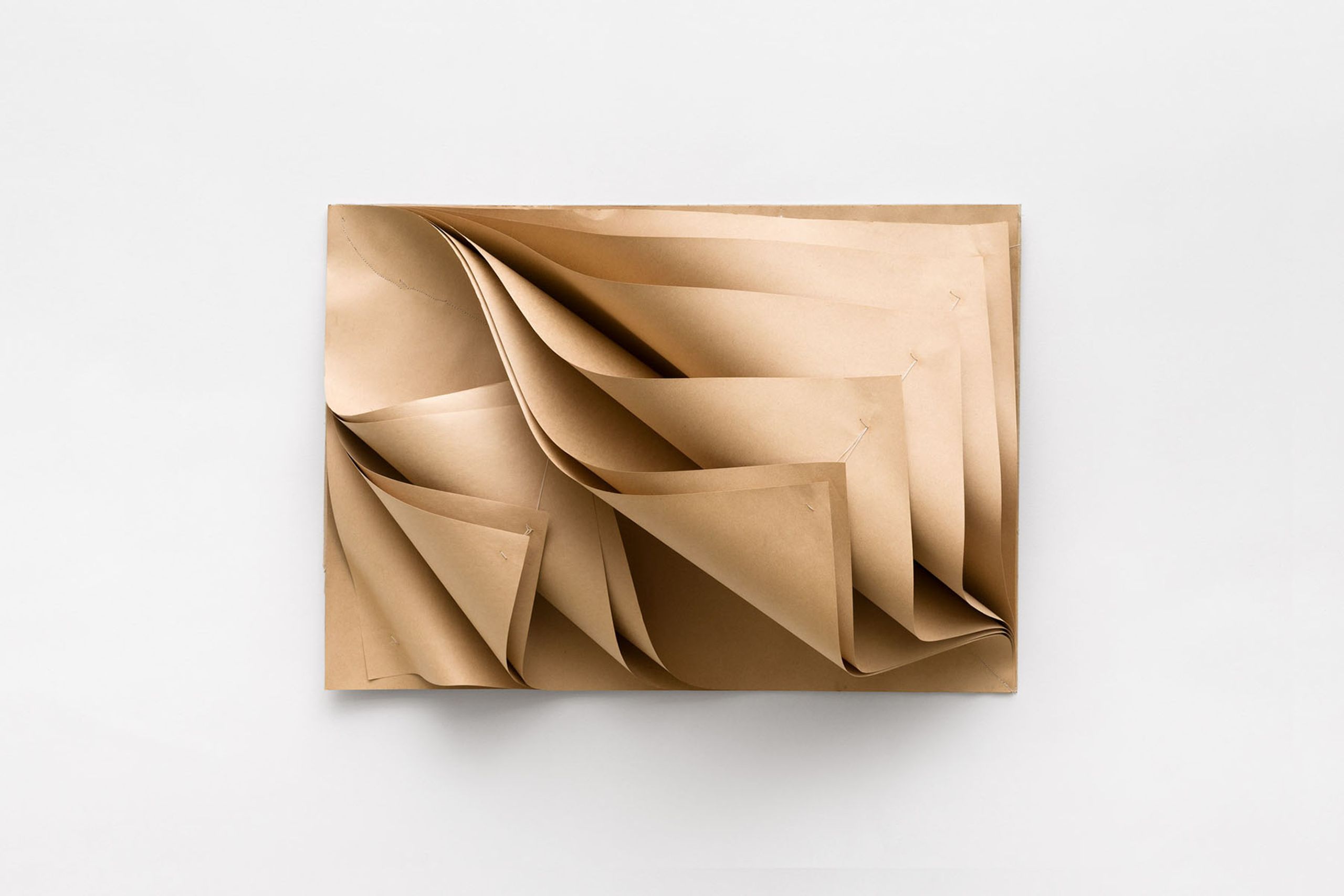 Abstract composition of layered and folded brown paper on a white background.