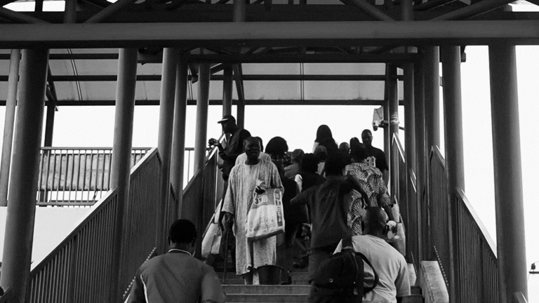 Black and white image of people on an elevated pedestrian walkway with stairs.