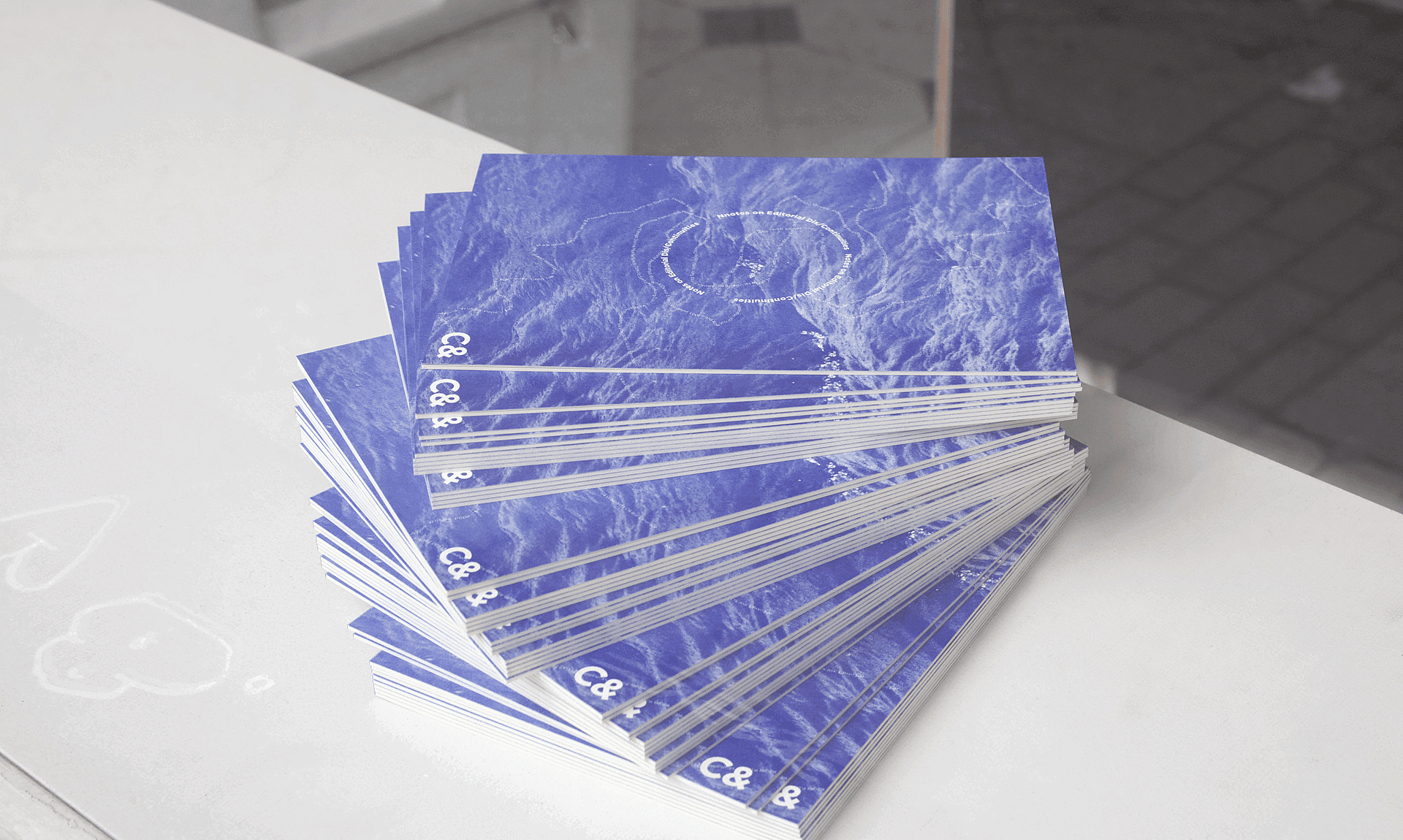 A fanned stack of blue publications with a wavy pattern and "C&" on the cover.