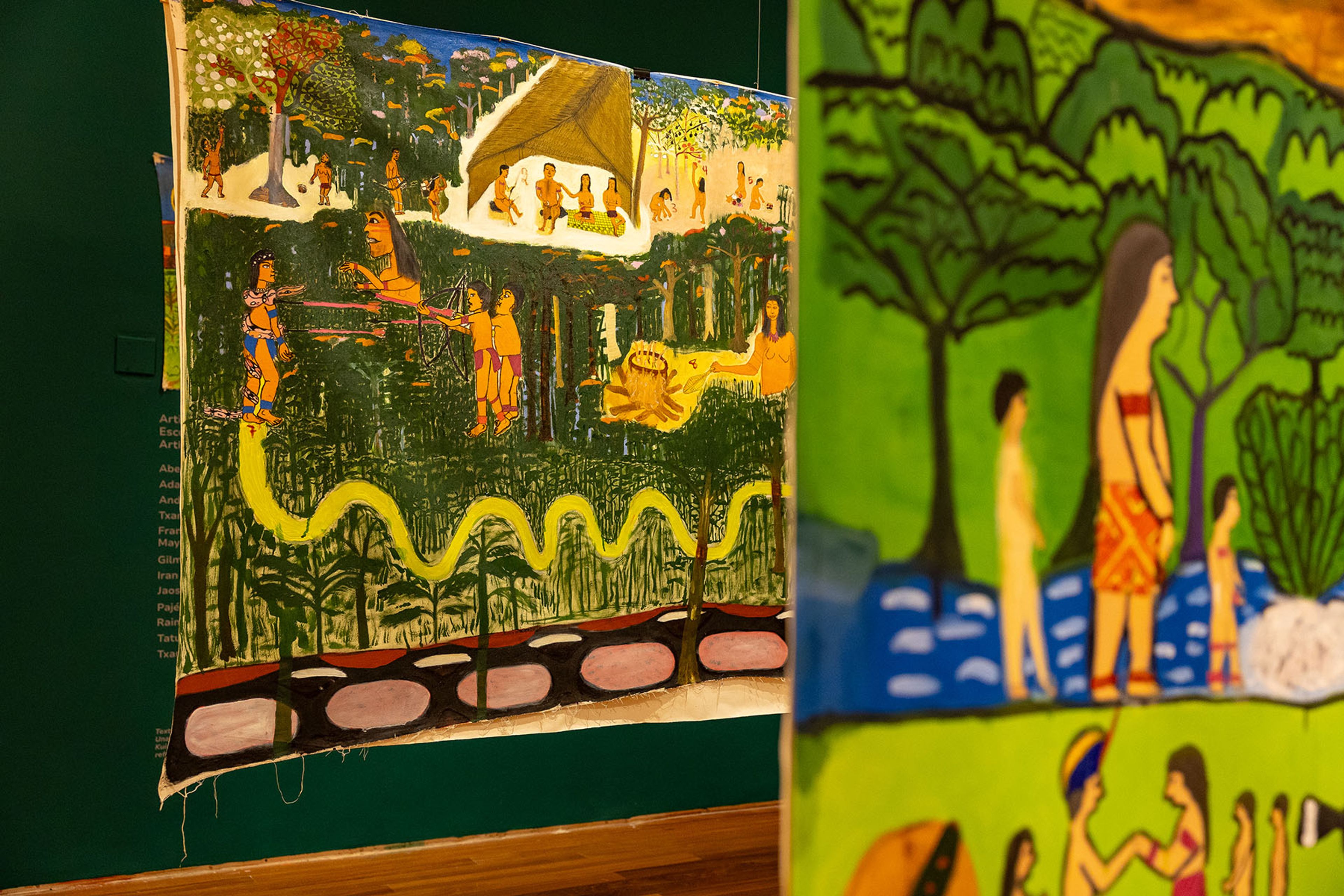 Two vibrant fabric paintings show stylized people and animals in a dense jungle.