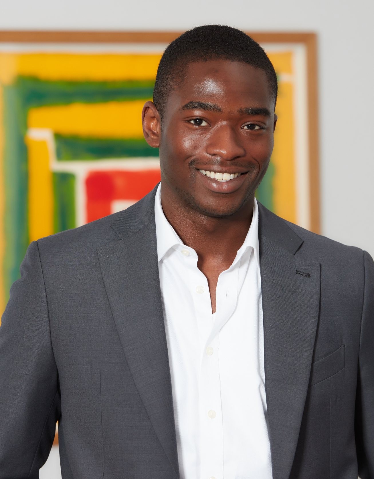 Smiling Black man in a grey suit and white shirt.