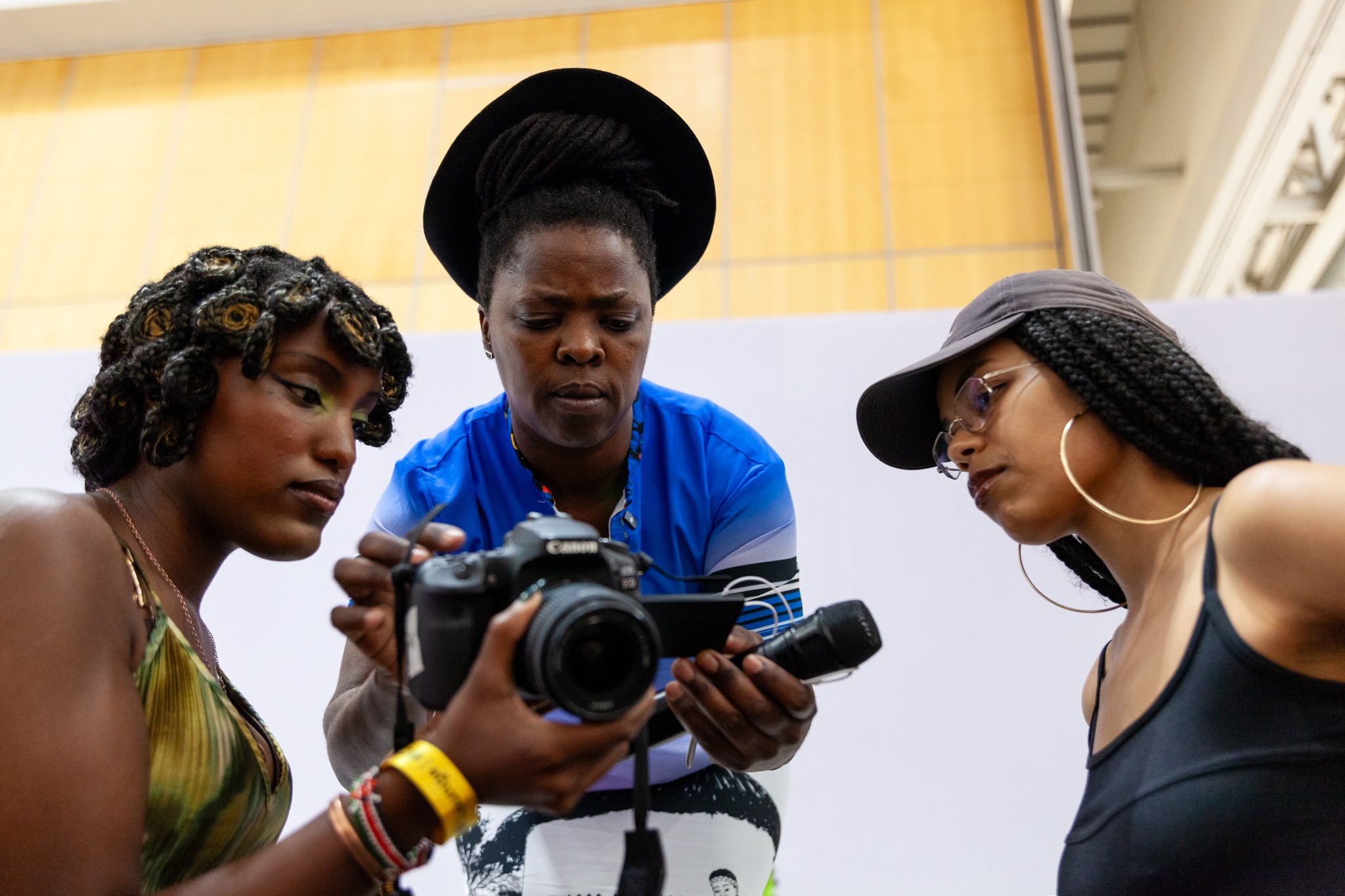 One person holds a camera while two others intently examine its screen.