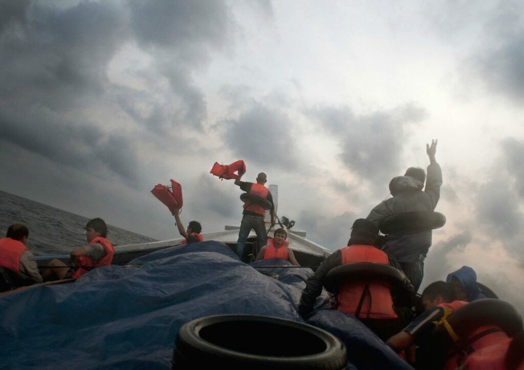 Barat Ali Batoor ’22 September, 2012, On the second day the boat is in trouble, taking on water - the passengers frantically wave their life jackets hoping to attract the attention of other boats.’ Courtesy of the artist