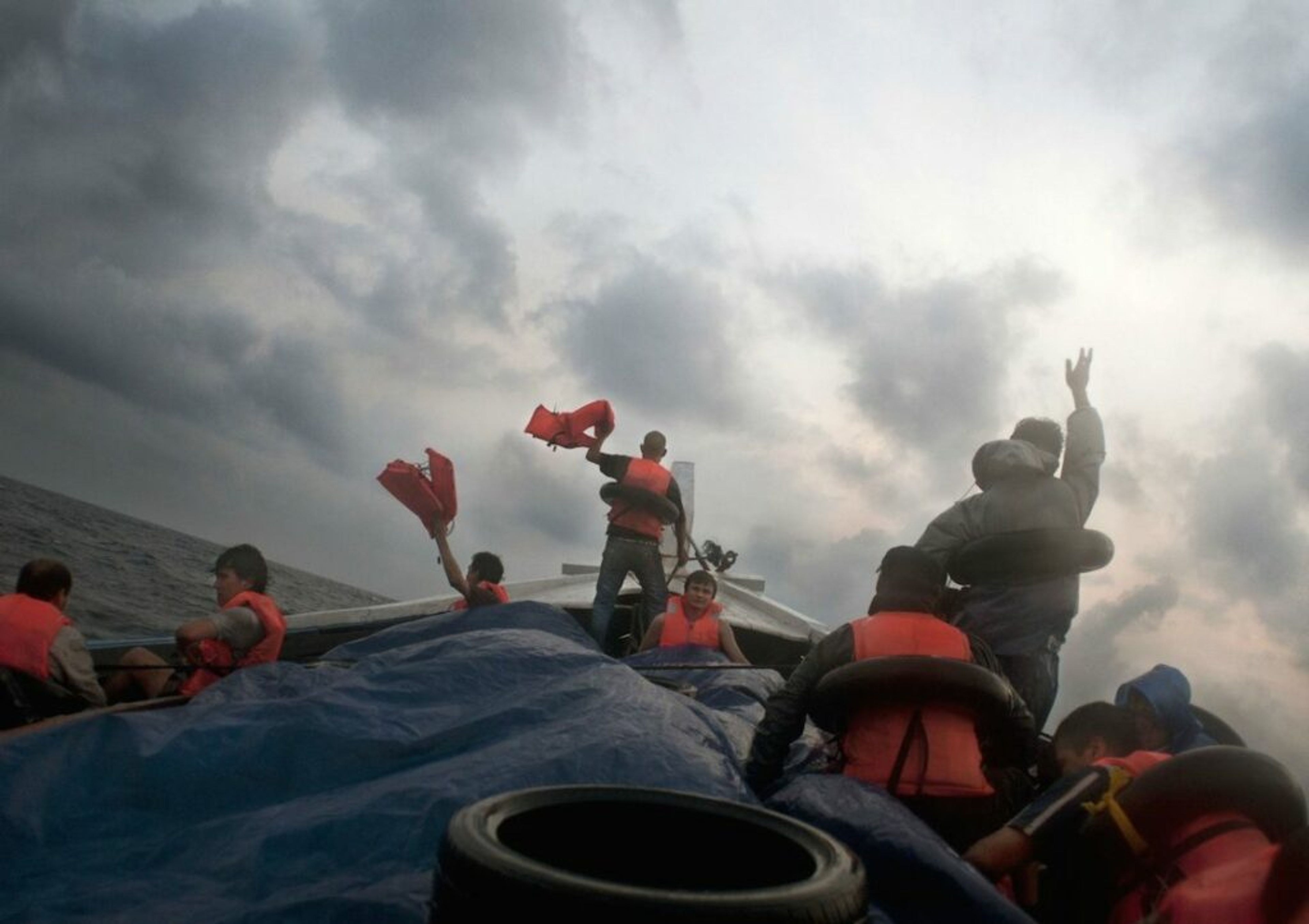Barat Ali Batoor ’22 September, 2012, On the second day the boat is in trouble, taking on water - the passengers frantically wave their life jackets hoping to attract the attention of other boats.’ Courtesy of the artist