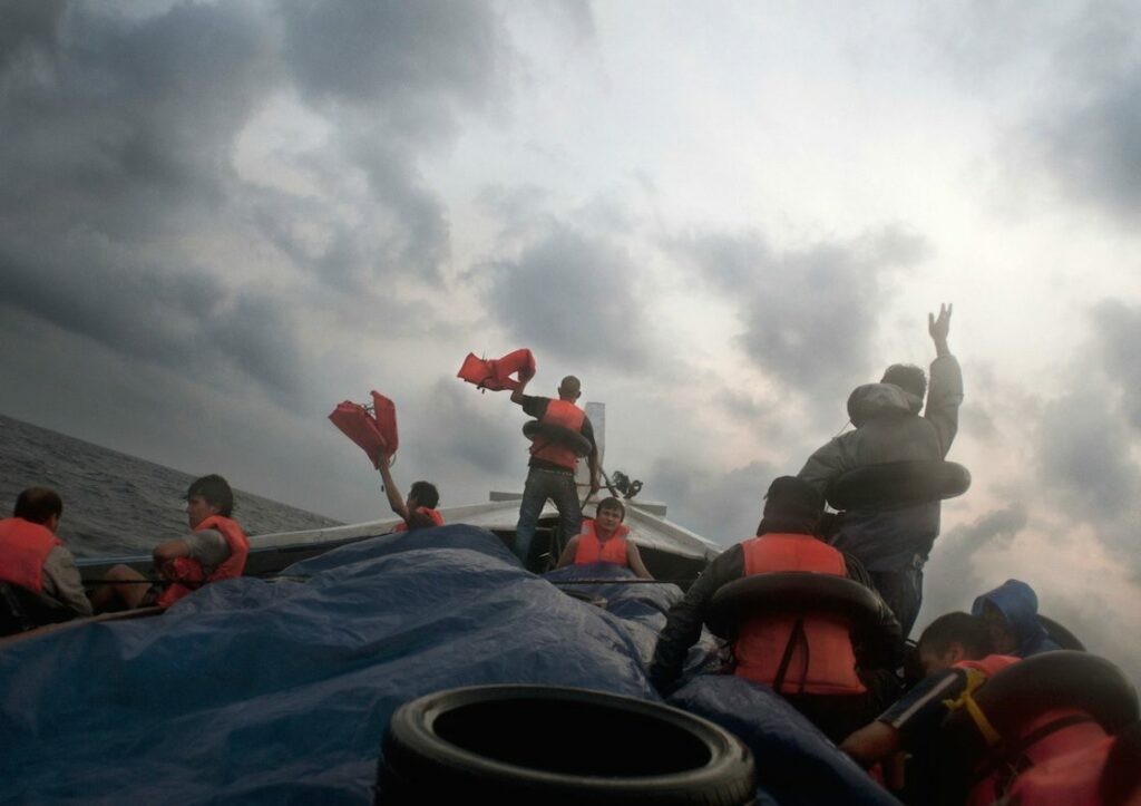 Barat Ali Batoor ’22 September, 2012, On the second day the boat is in trouble, taking on water - the passengers frantically wave their life jackets hoping to attract the attention of other boats.’ Courtesy of the artist