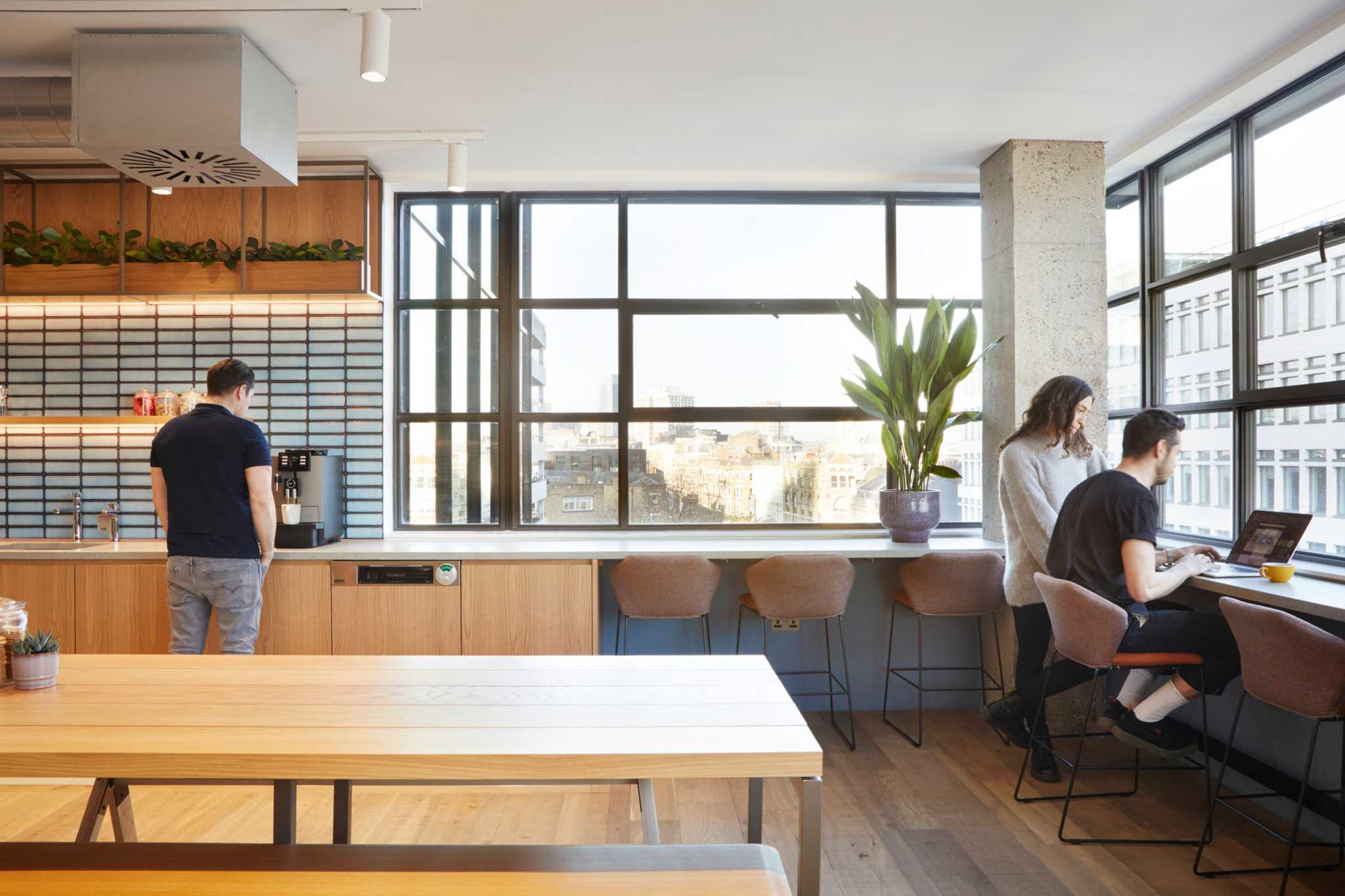 Coworkers using a communal kitchen and shared workspace in a London office space.