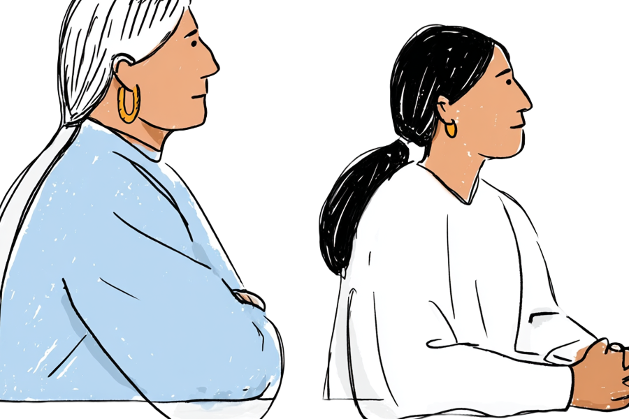 Two Native people sitting next to each other, one an elder white hair