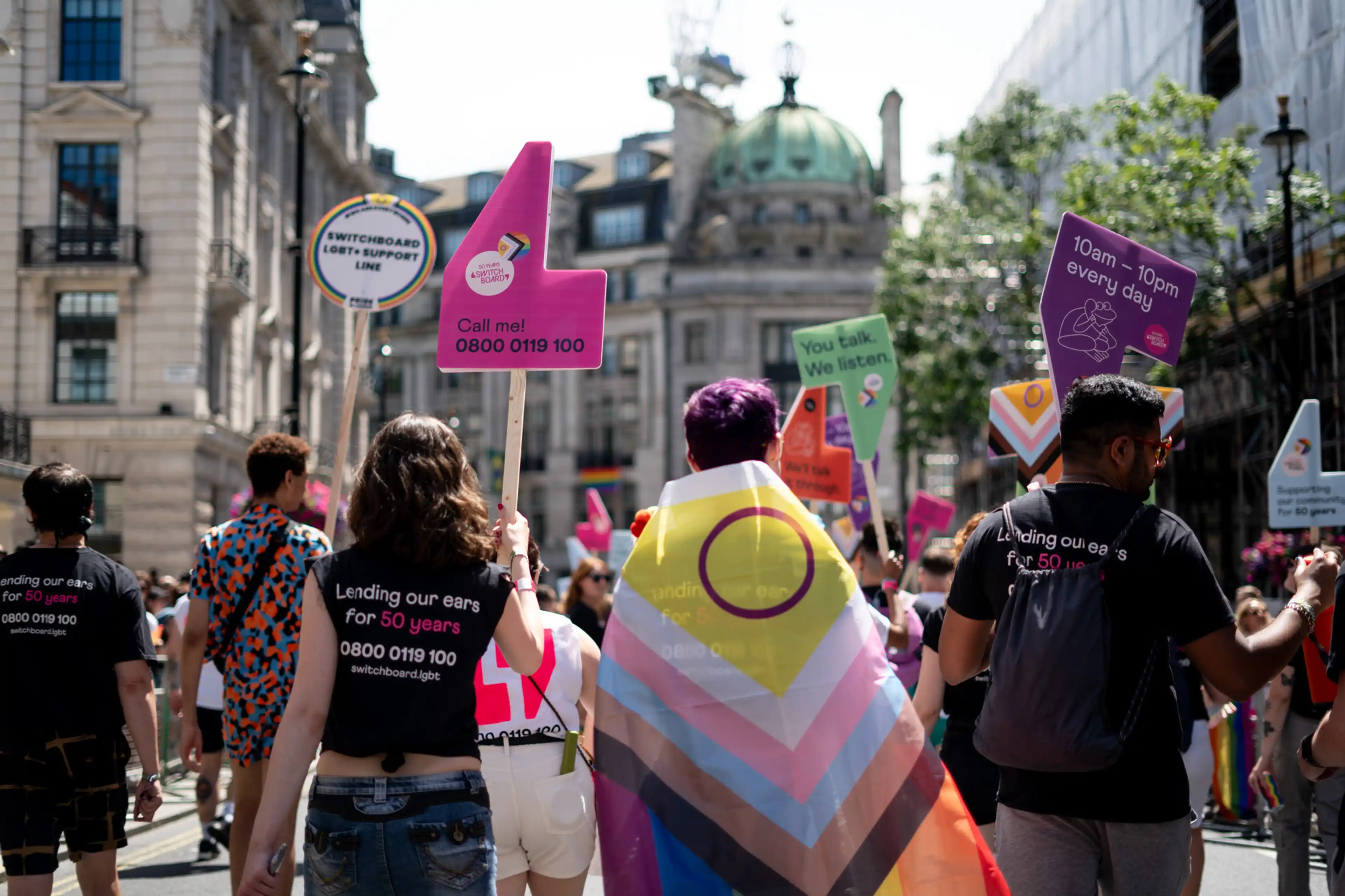 pride flag wrapped around person marching in pride parade