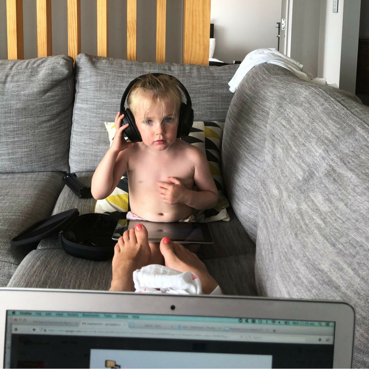 Child on couch, seen from behind mum’s laptop