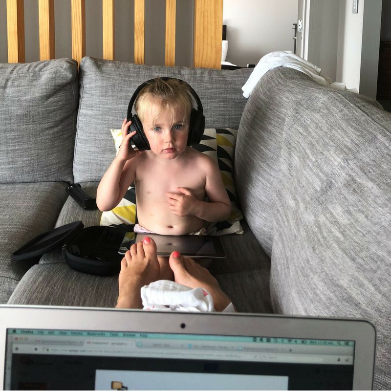 Child on couch, seen from behind mum’s laptop
