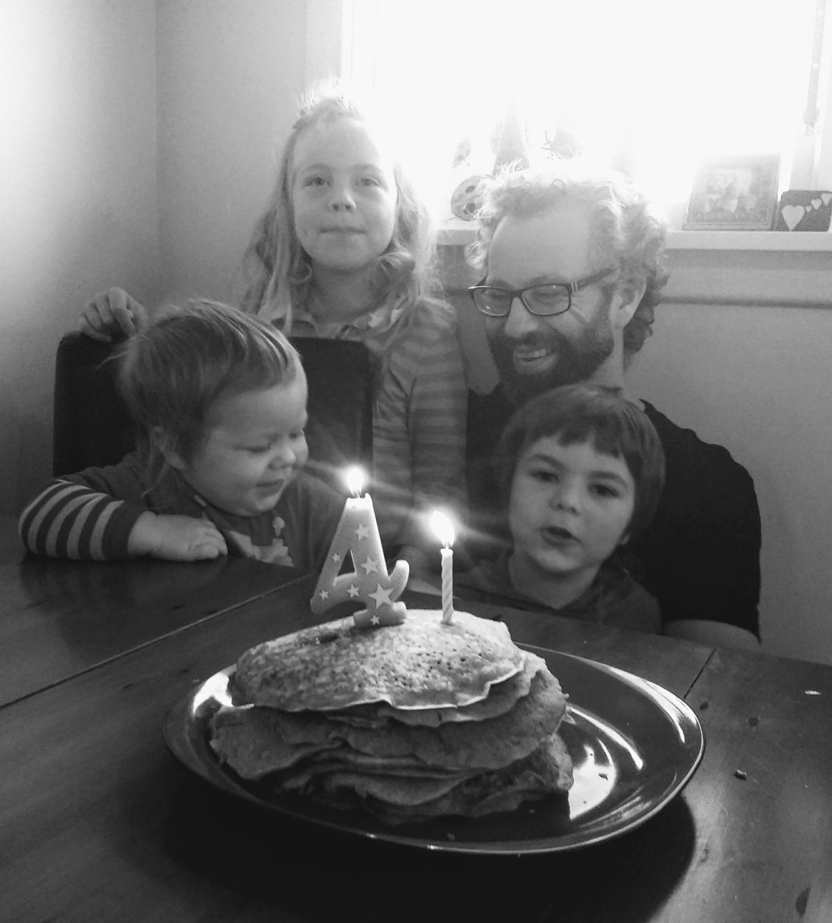 Dad crouched with 3 kids and pancake birthday stack