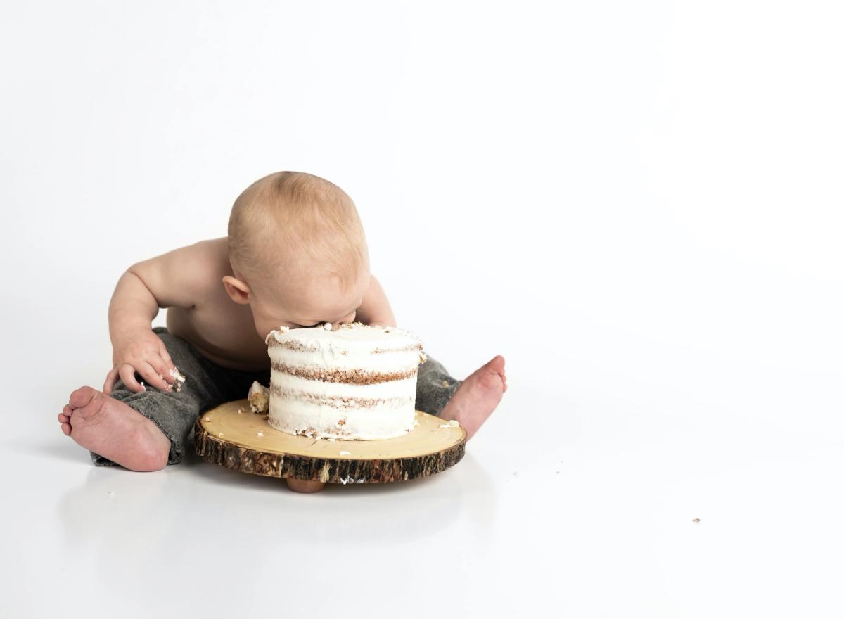 Baby sitting on the floor with its face in a cake