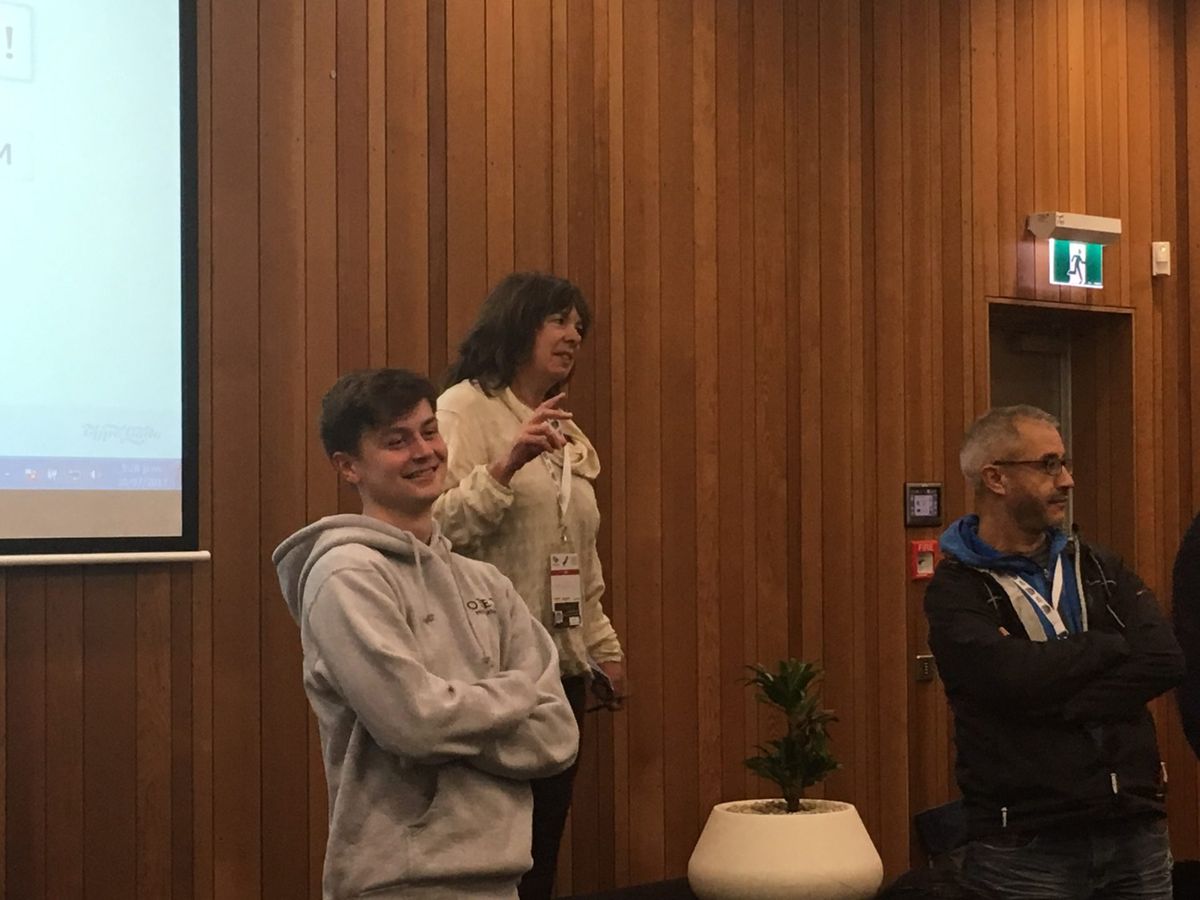 3 people standing at the front of a room